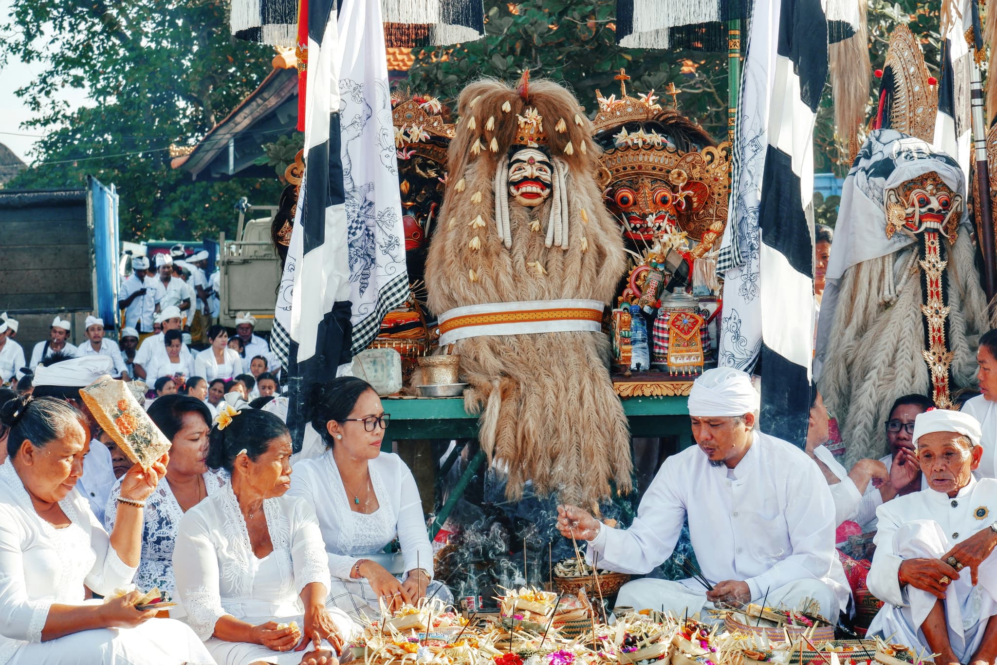 Local people of Bali sitting next to each other in front of a festival parade for Nyepi in Bali