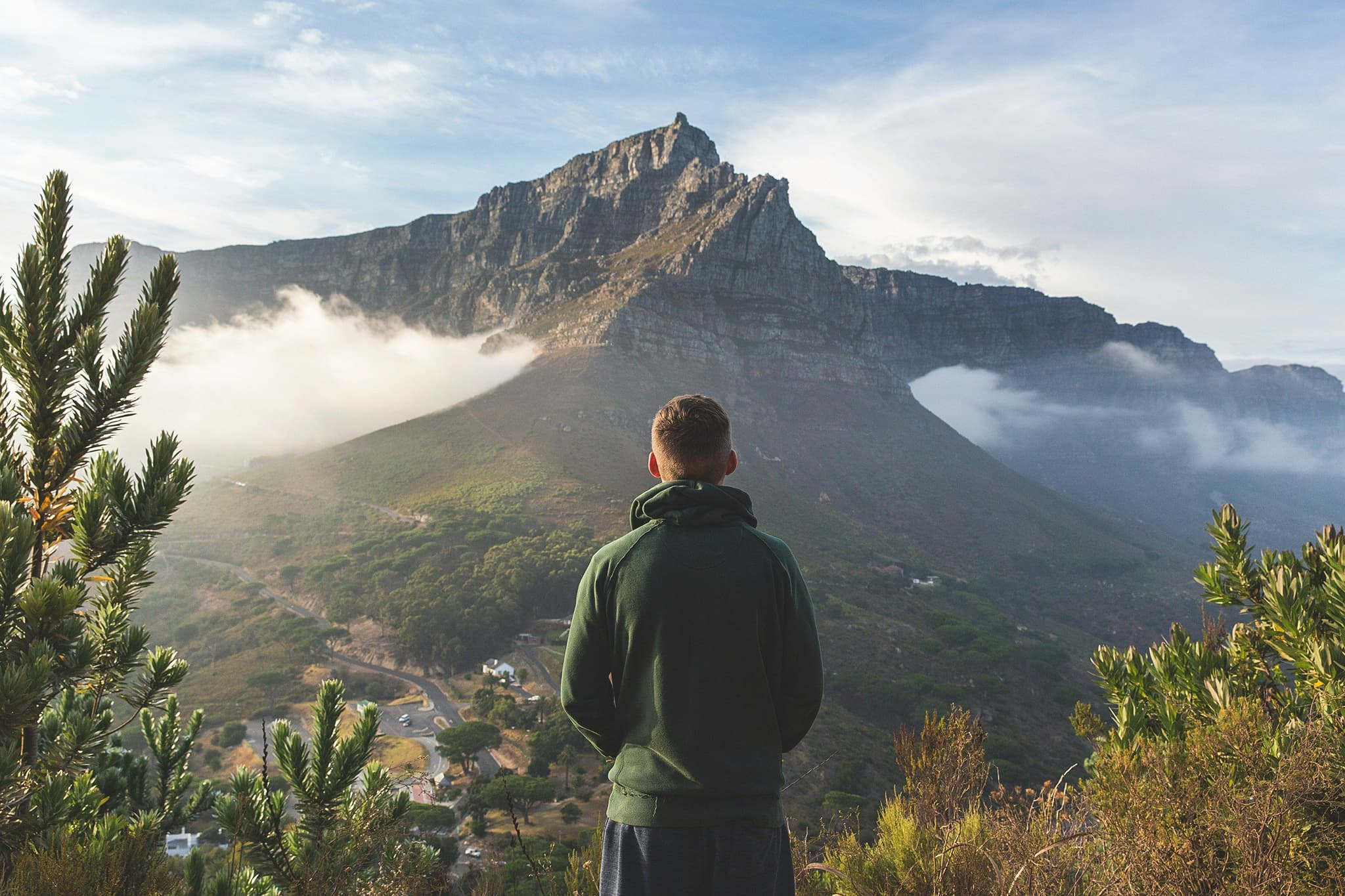Male traveller standing on a viewpoint overlooking table mountain with clouds