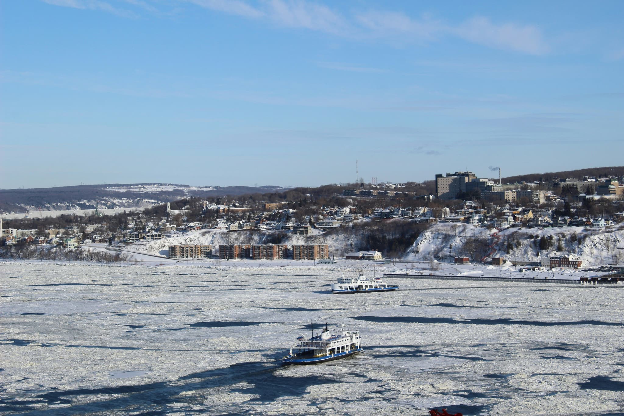Boats navigating the frozen St. Lawrence River near Quebec City in winter, the same stretch of river where the carnival's ice canoe race is held.