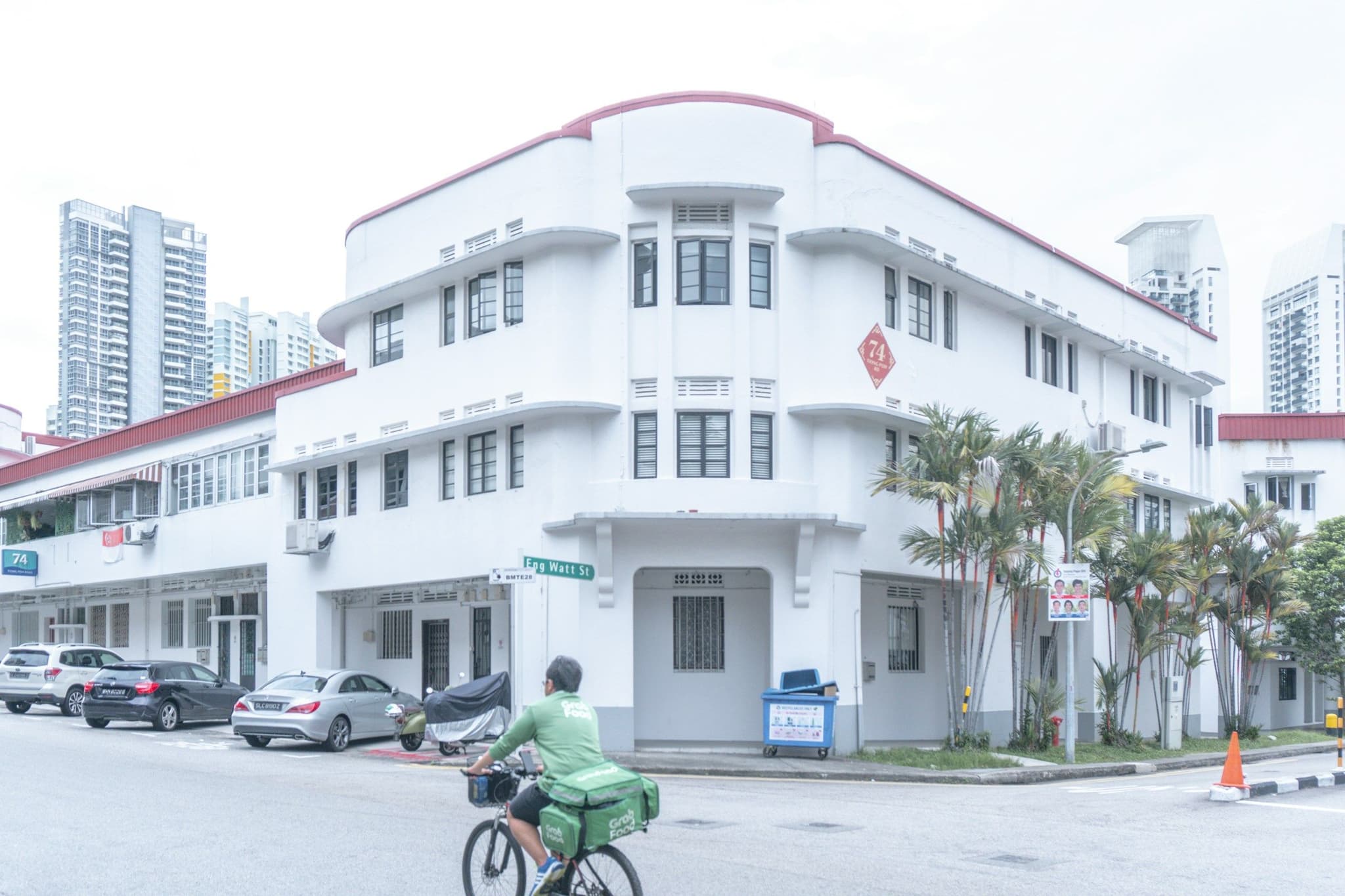 A cyclist passing a white low-rise apartment block