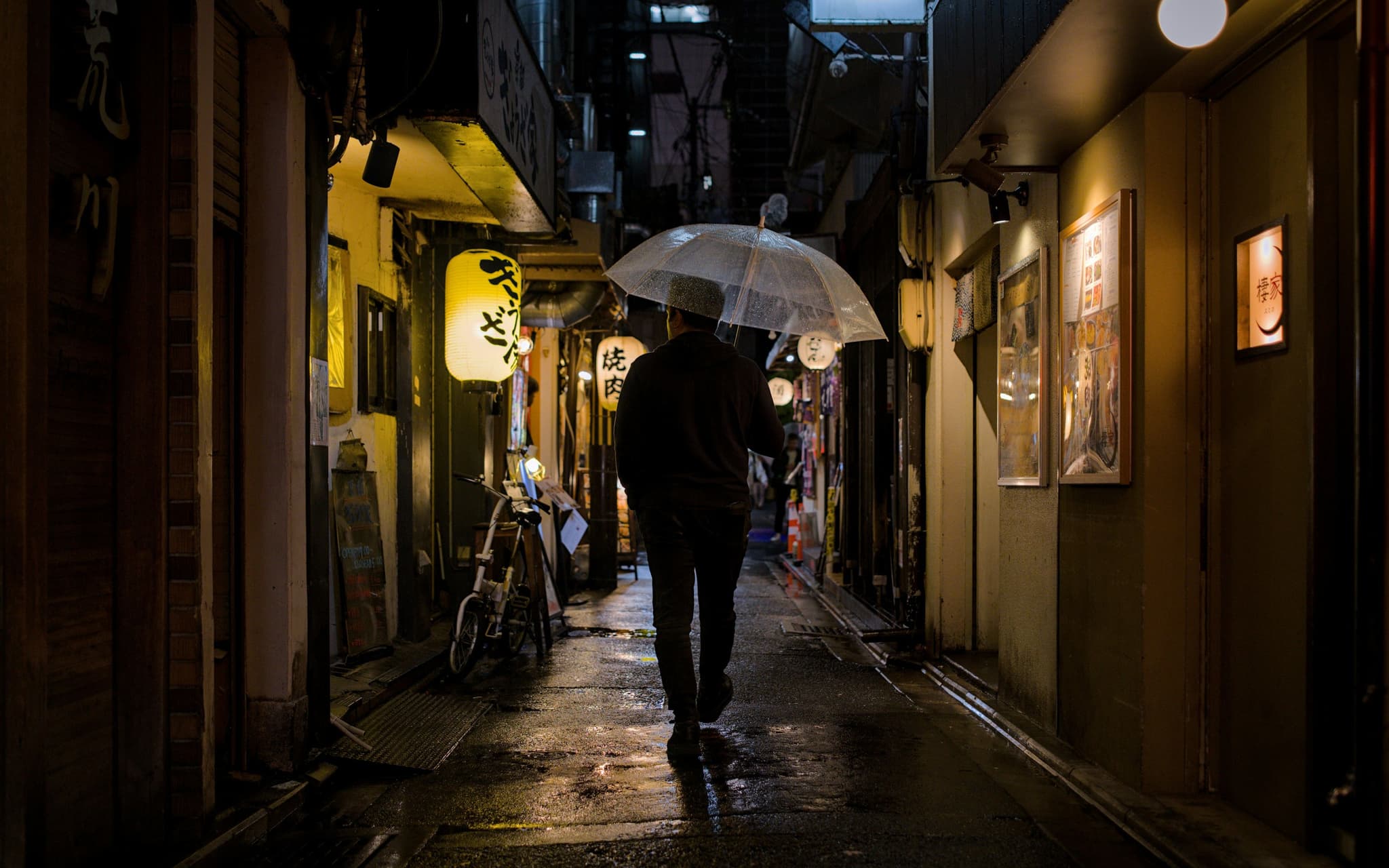 Someone walking with an umbrella through a rainy Kyoto street during Japan's rainy season