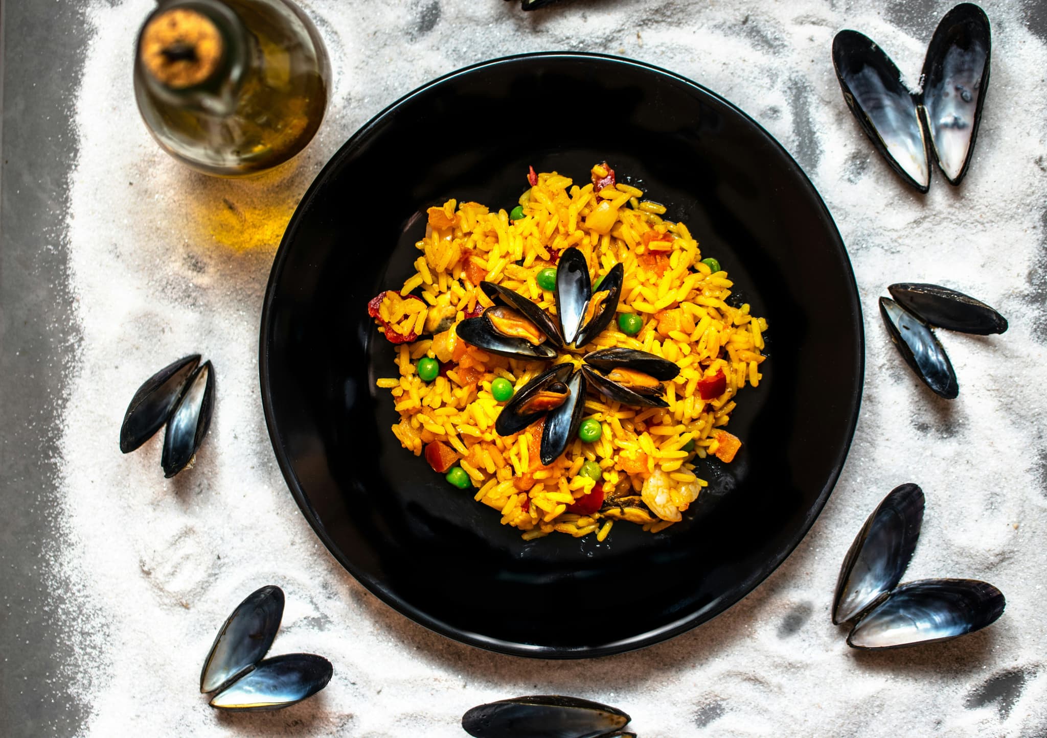 Black plate with Aarroz de marisco and mussles next to it.