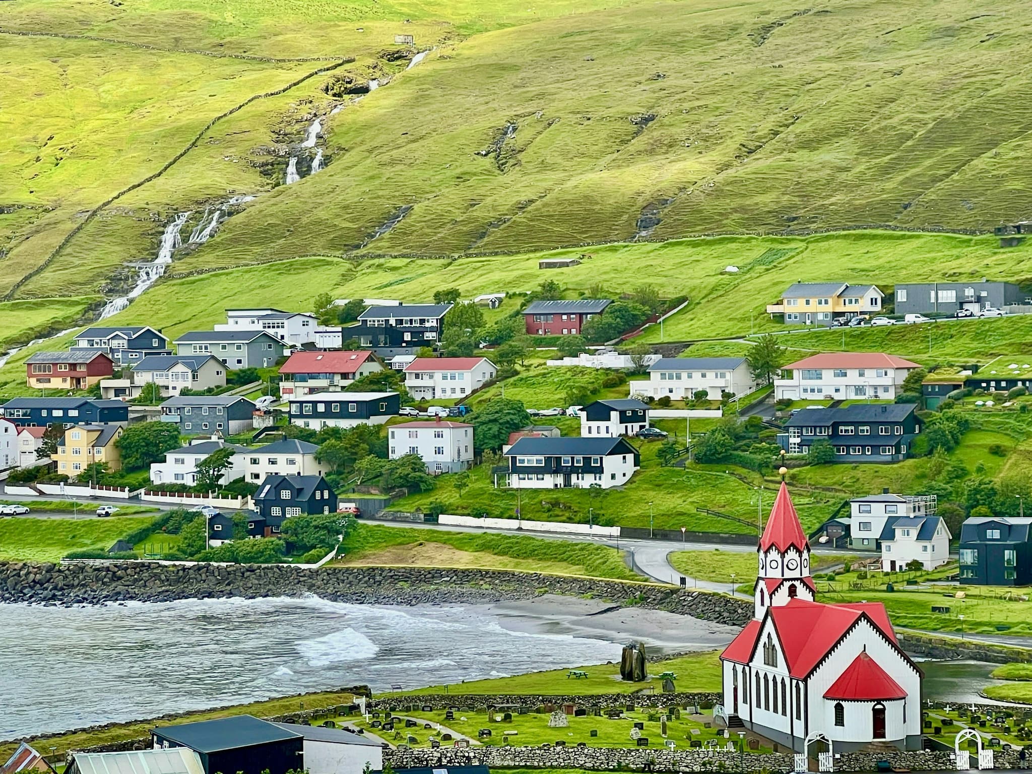 Red churchtop and houses on a green hill in Vík í Mýrdal