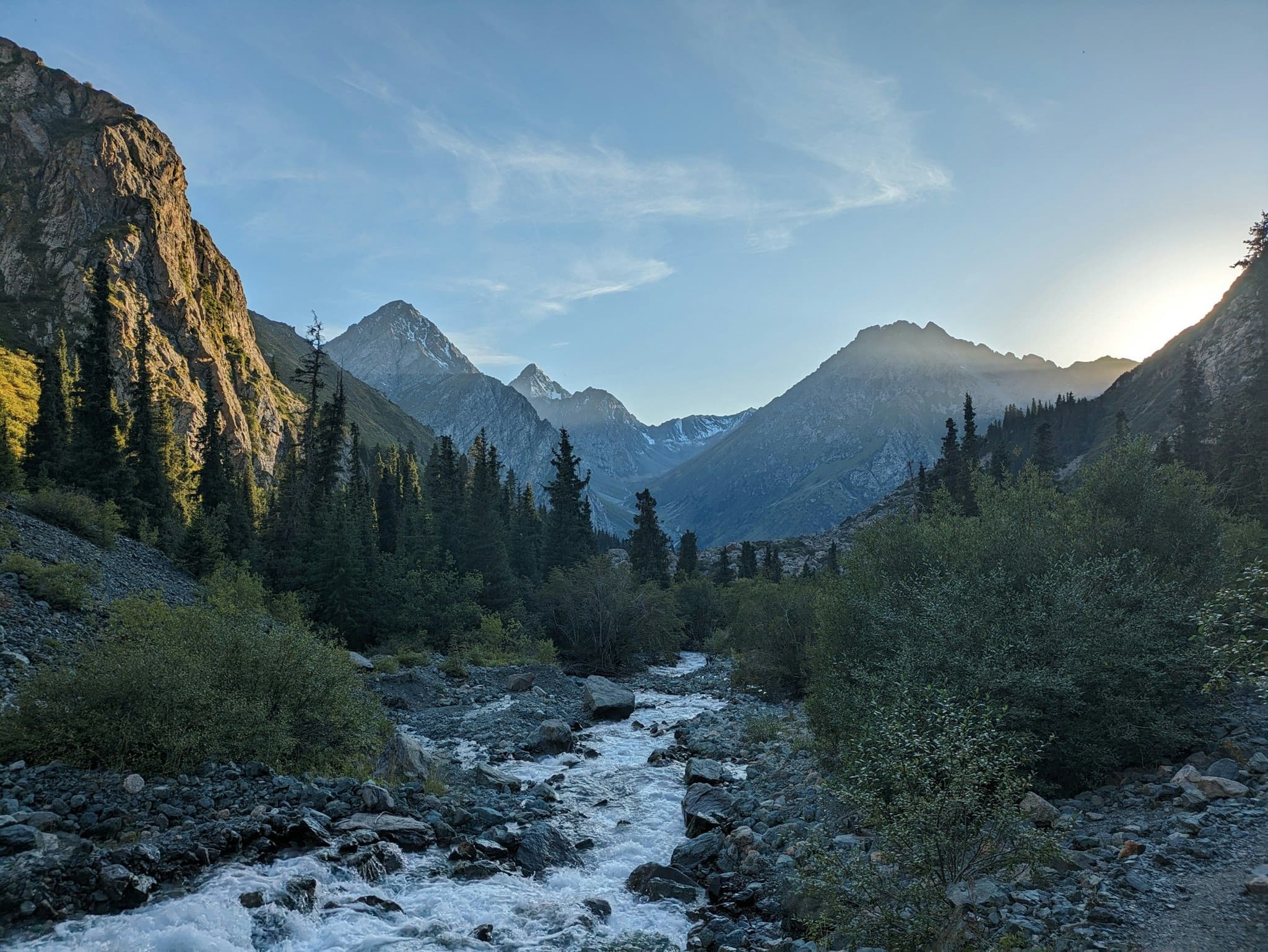 A river through spruce forest at sunset on the Ala-Kul trek