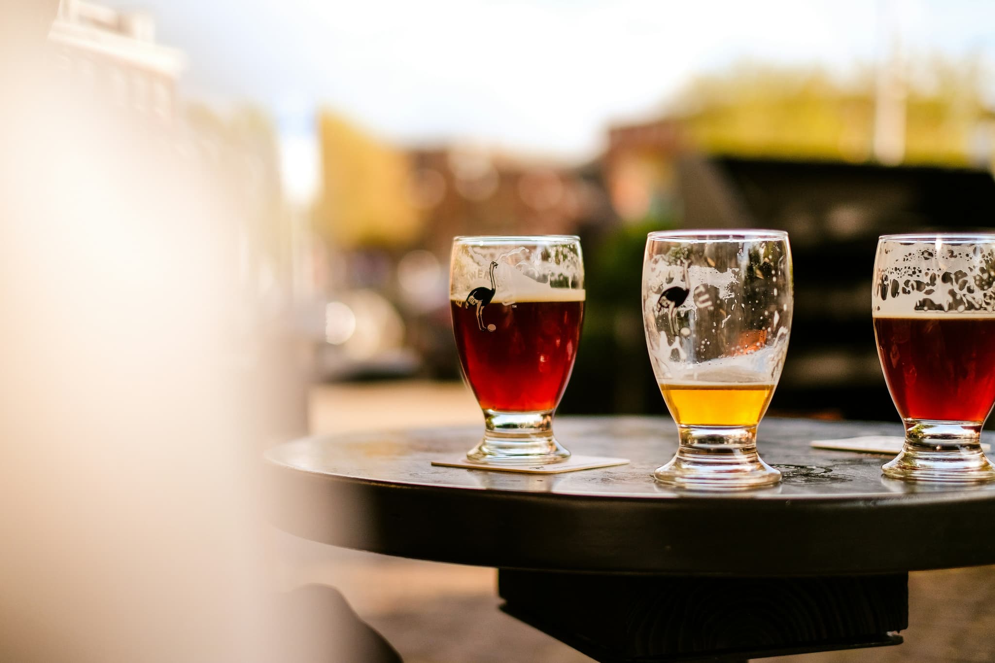 Three glasses of beers in the sun outside on a table