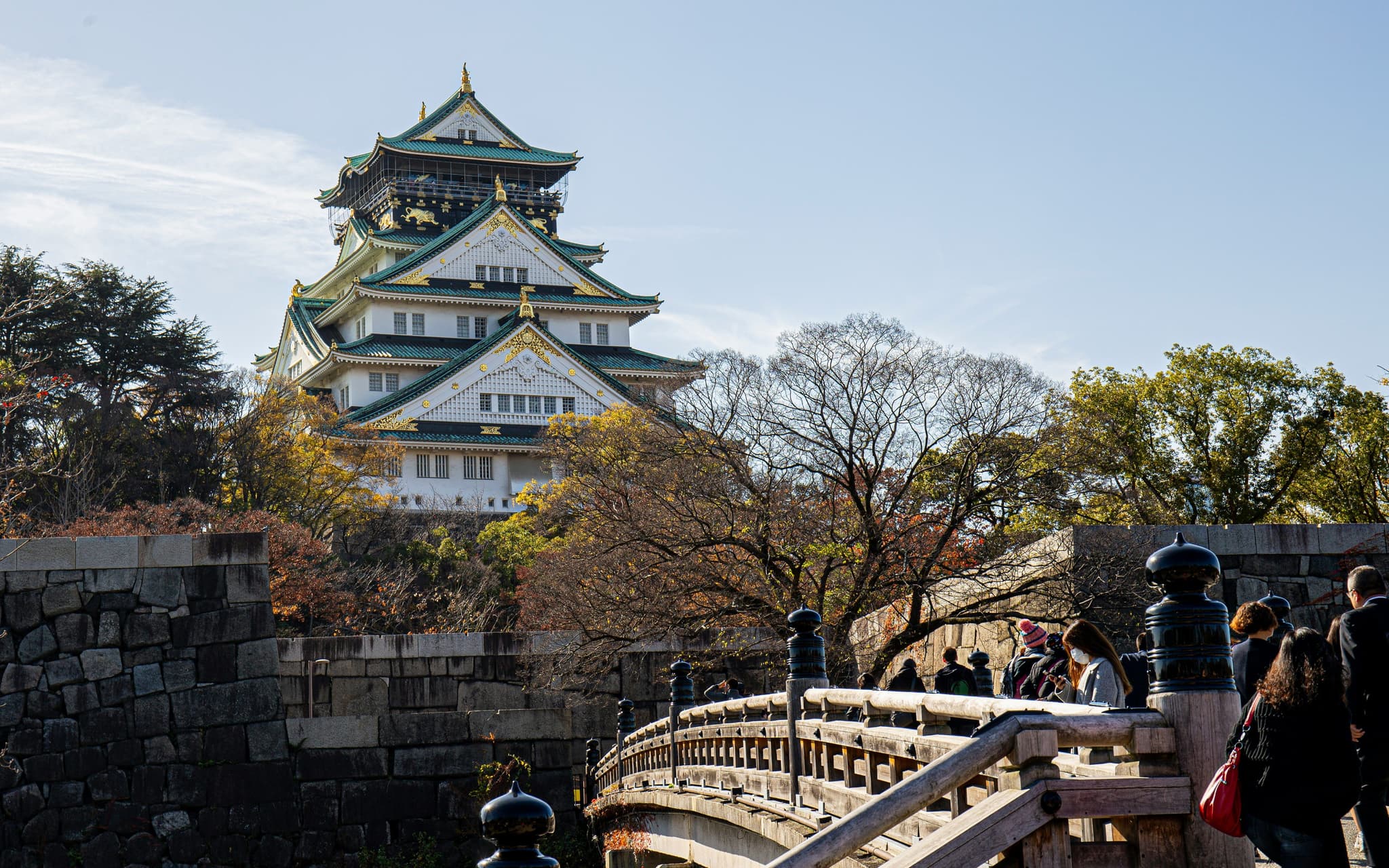 Temple in Osaka surrounded with people on a wooden bridge