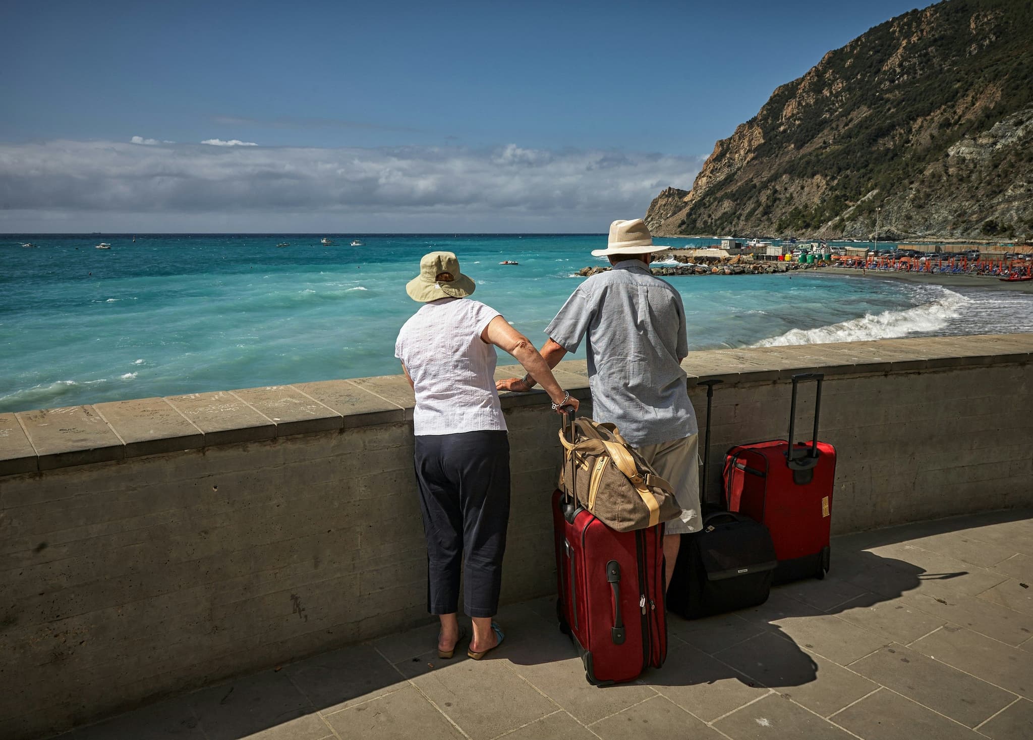Two tourist with suitcases standing by the ocean