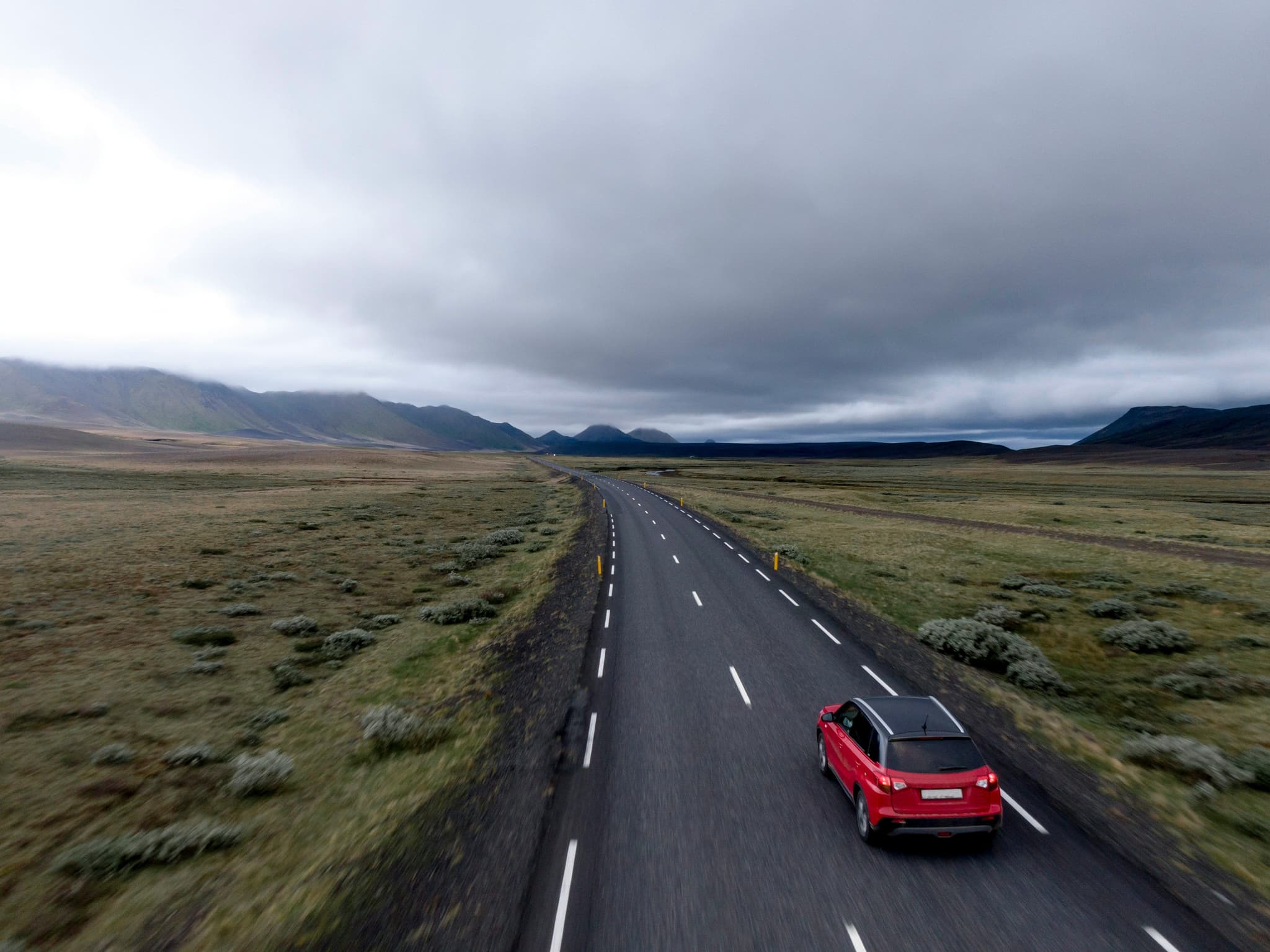 A red car from above driving a road in Ireland on a cloudy day