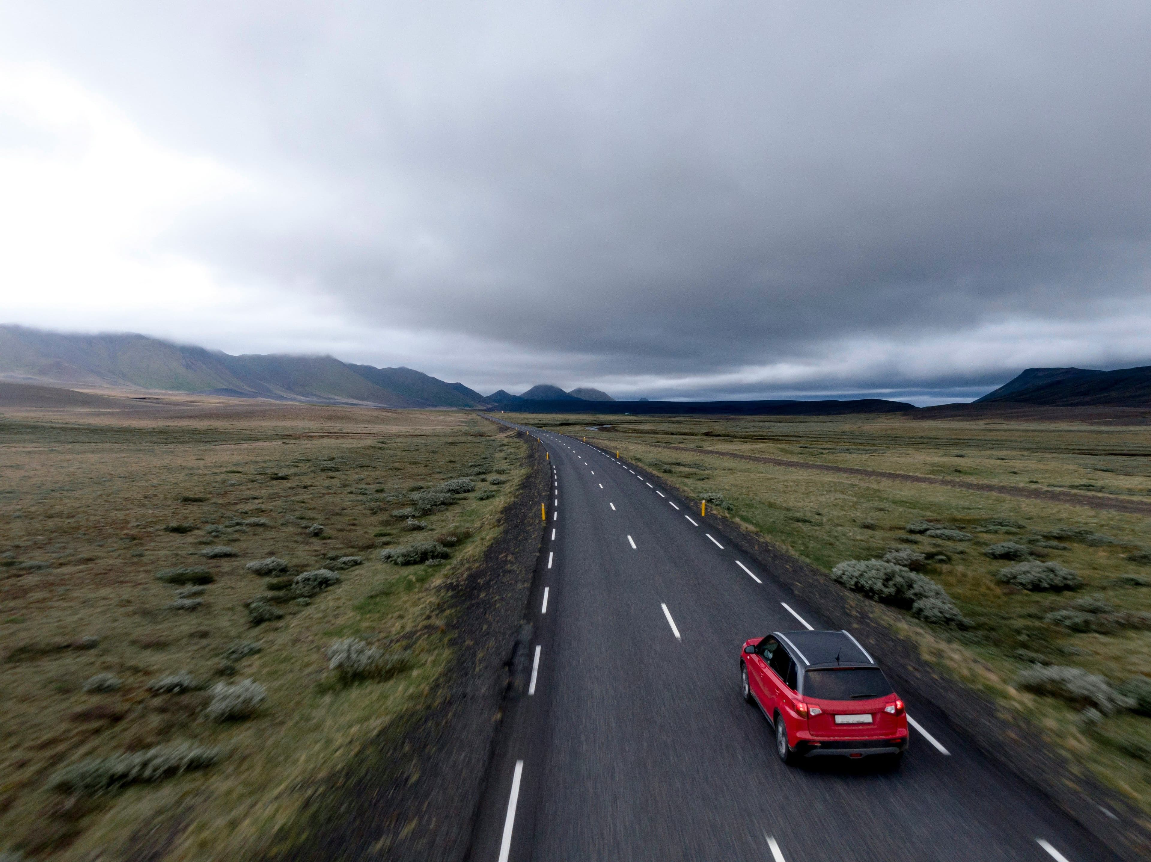 A red car from above driving a road in Ireland on a cloudy day