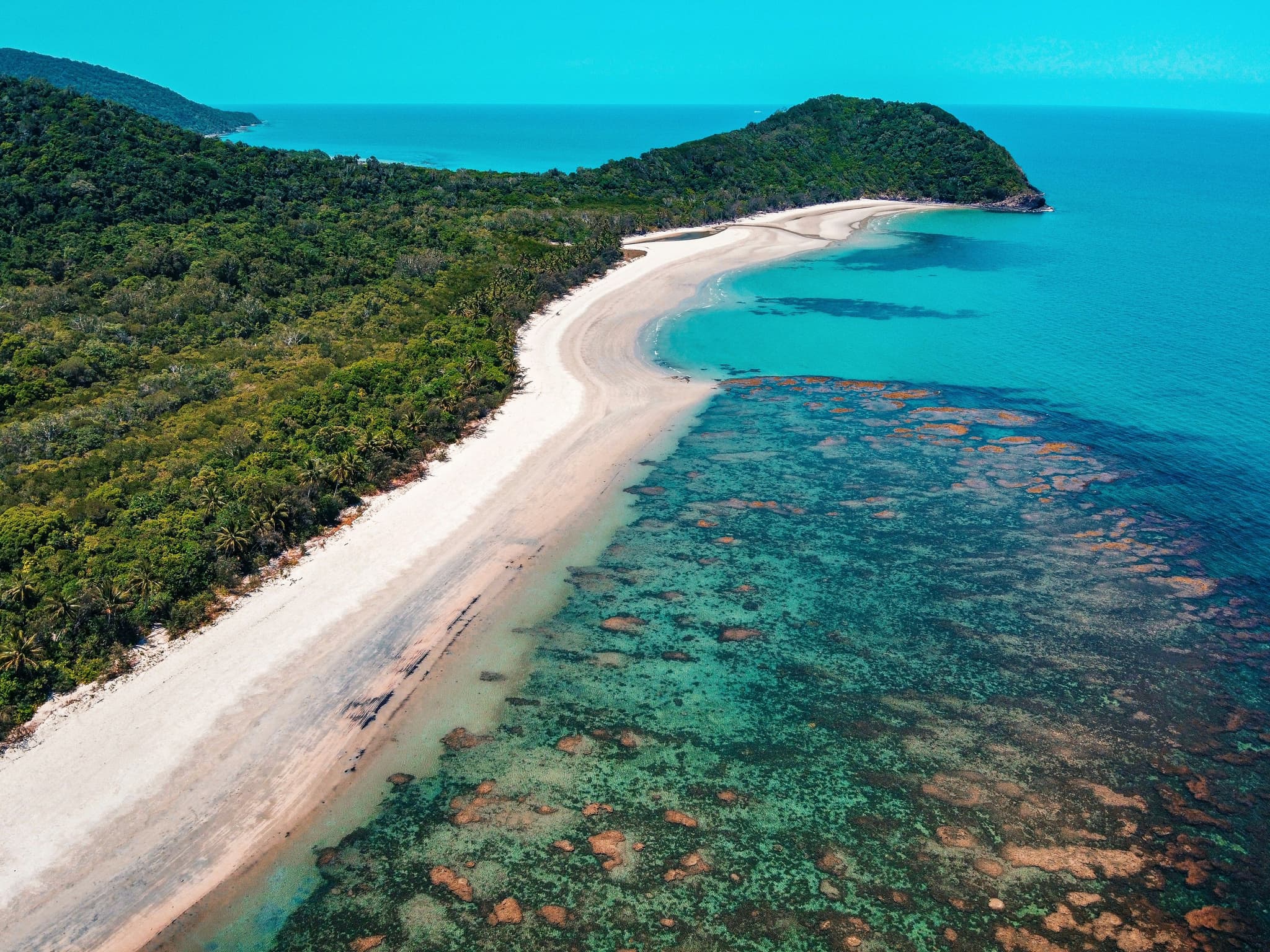 Aerial view of The Great Barrier Reef: green forest, white sand and turqoise water