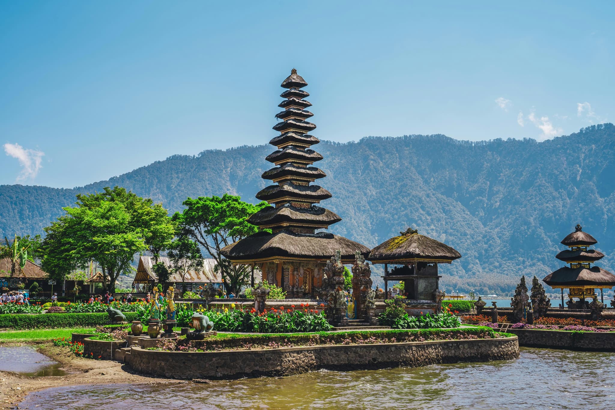 Temple in bali on a lake with mountains in the background on a sunny day