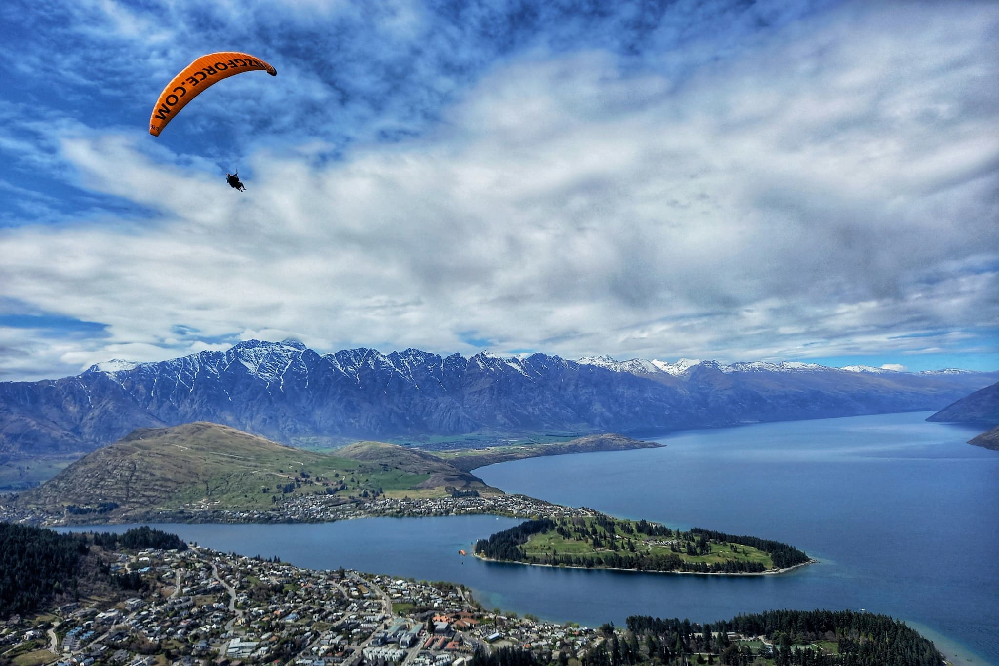 Paraglider in the sky in Queenstown aerial picture from above looking over the sea and peninsula