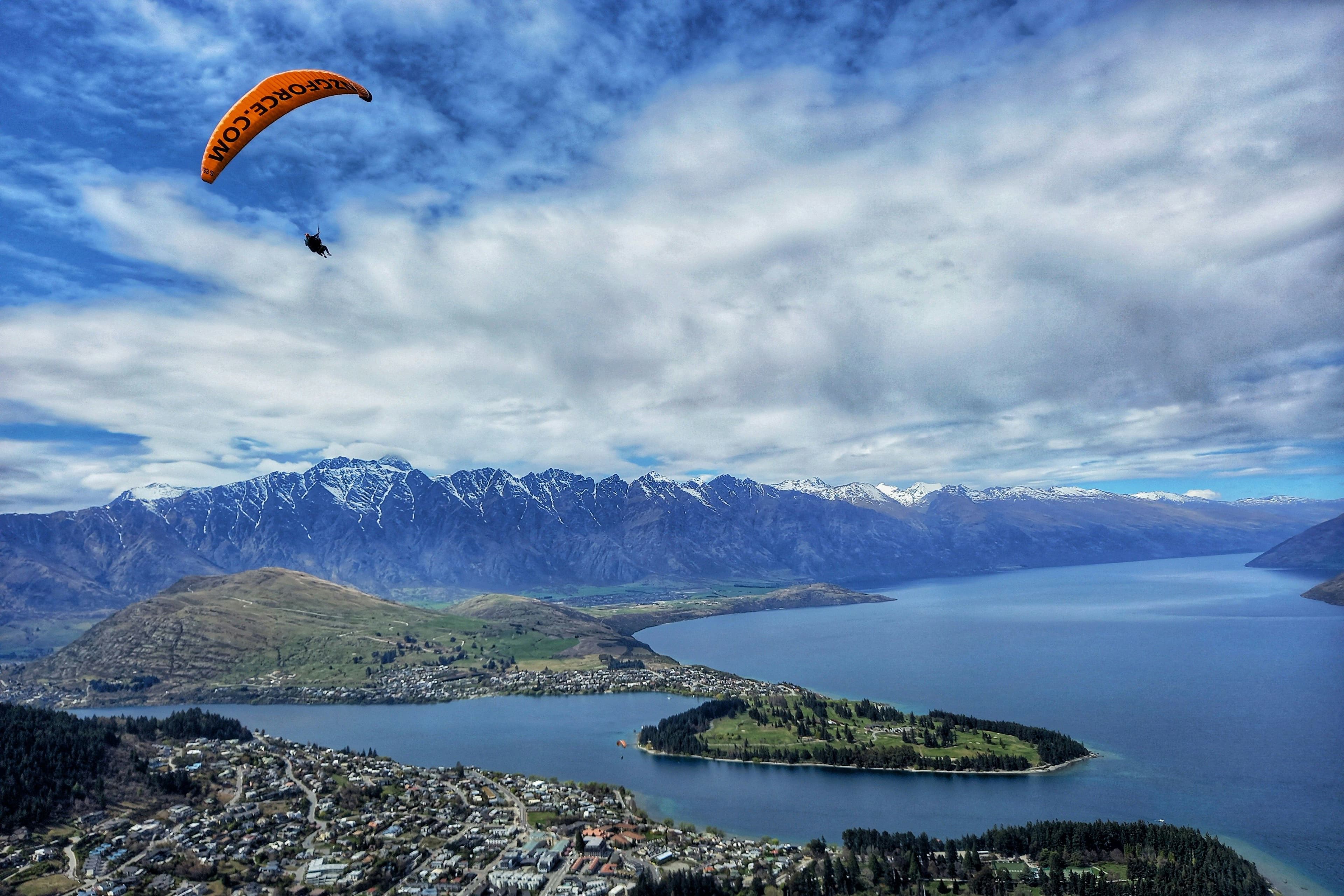 Paraglider in the sky in Queenstown aerial picture from above looking over the sea and peninsula