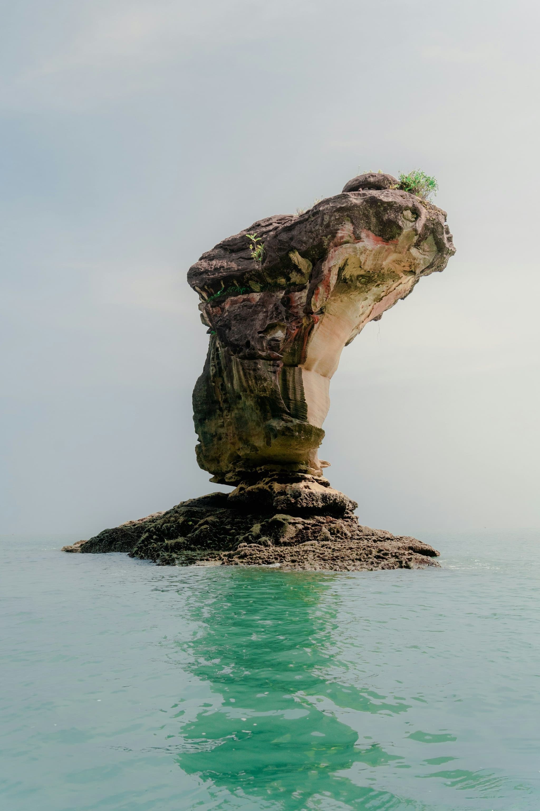 A rock sea stack standing in shallow water off the coast