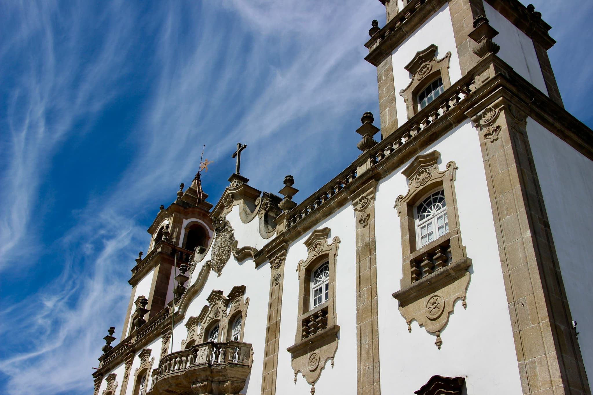 A white with brown building in Viseu from up close with a blue sky