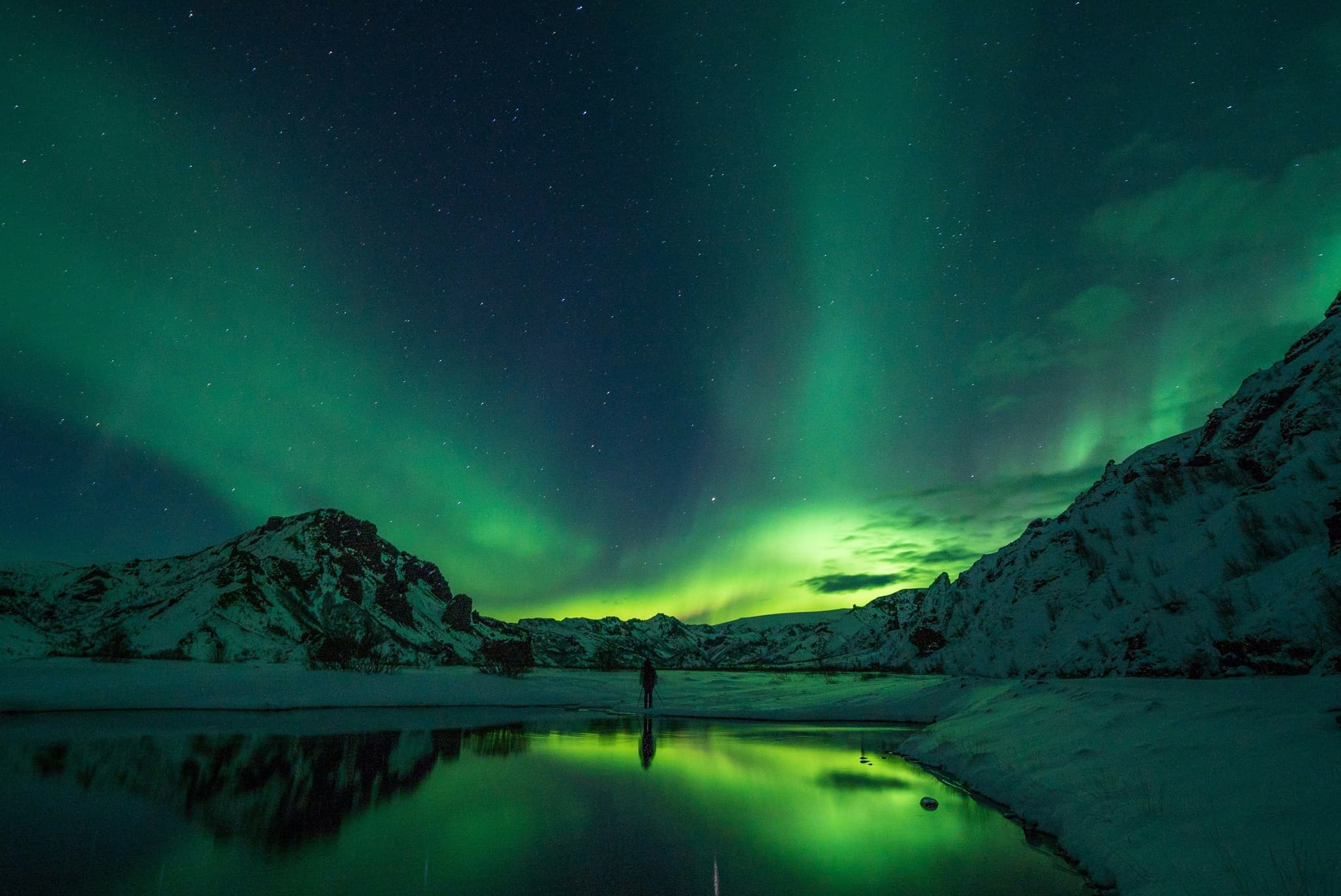 Green northern lights swirling under a dark Icelandic sky.
