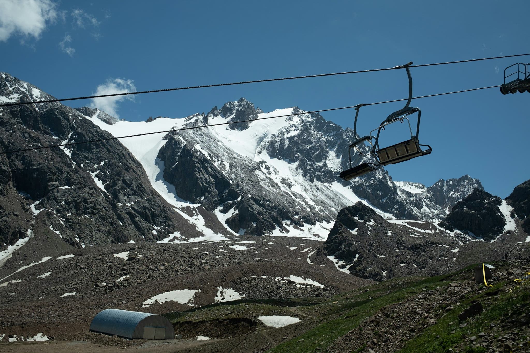A chairlift climbing snowy slopes near the top of Shymbulak