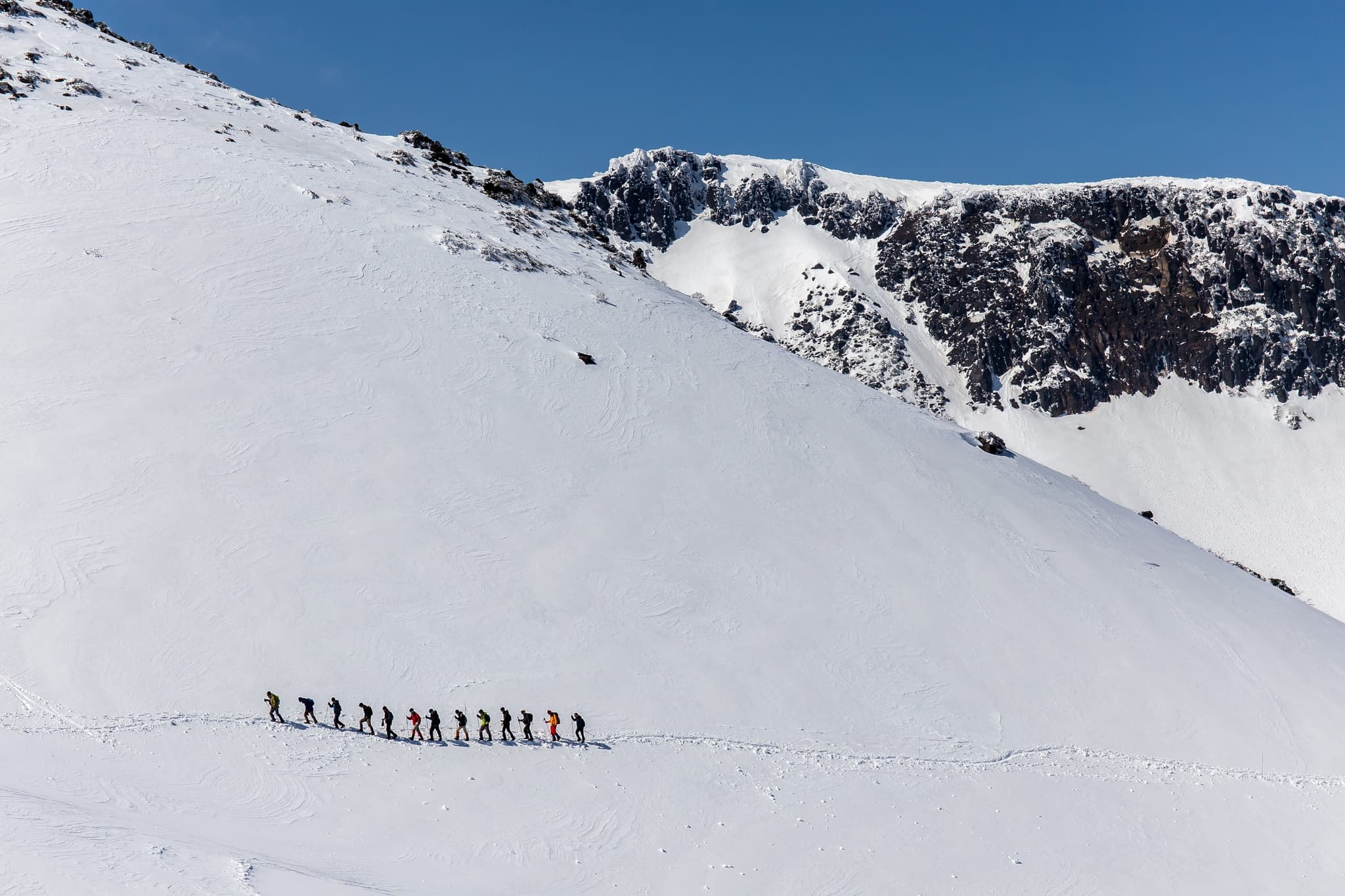 A group of hikers walking in the snow on a snowy mountain