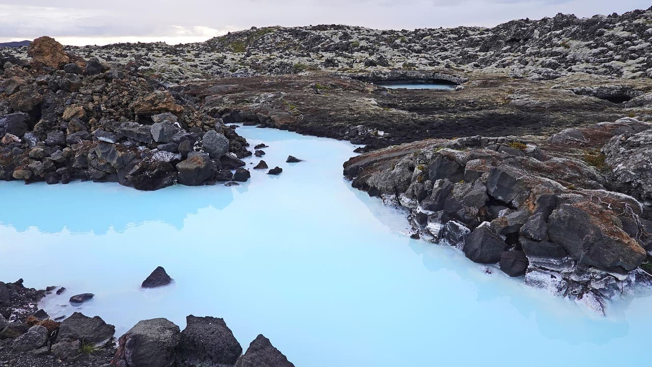 Turquoise geothermal water surrounded by dark volcanic rocks near the Blue Lagoon in Iceland.