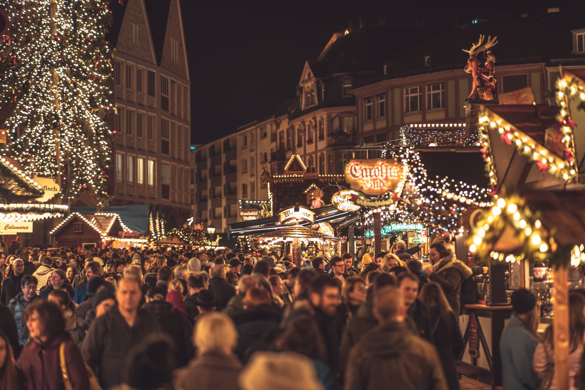 Christmas market with market stalls with christmas lights with many people at night