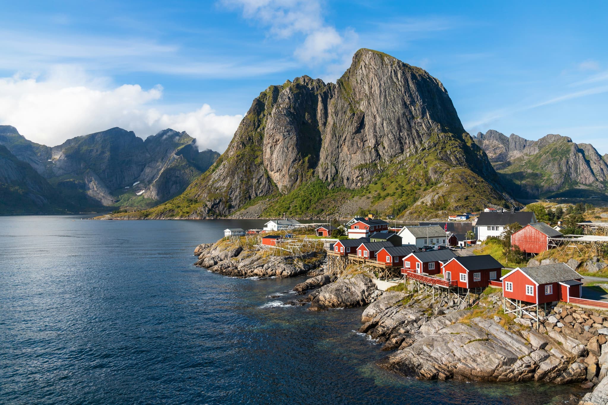 Red houses on stone edge near lake in The Lofoten Islands, mountain in the background