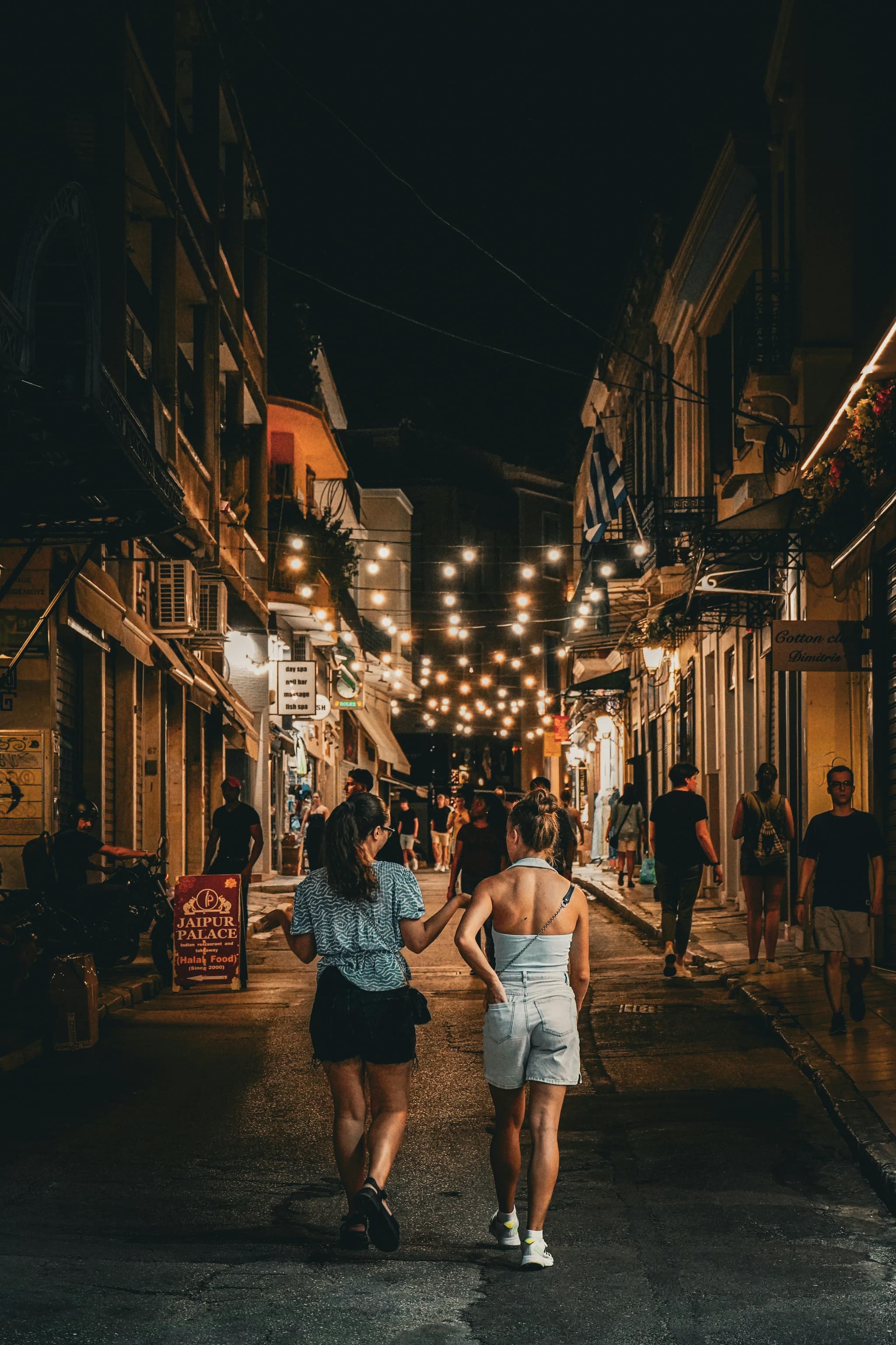 2 girls walking a street with lights