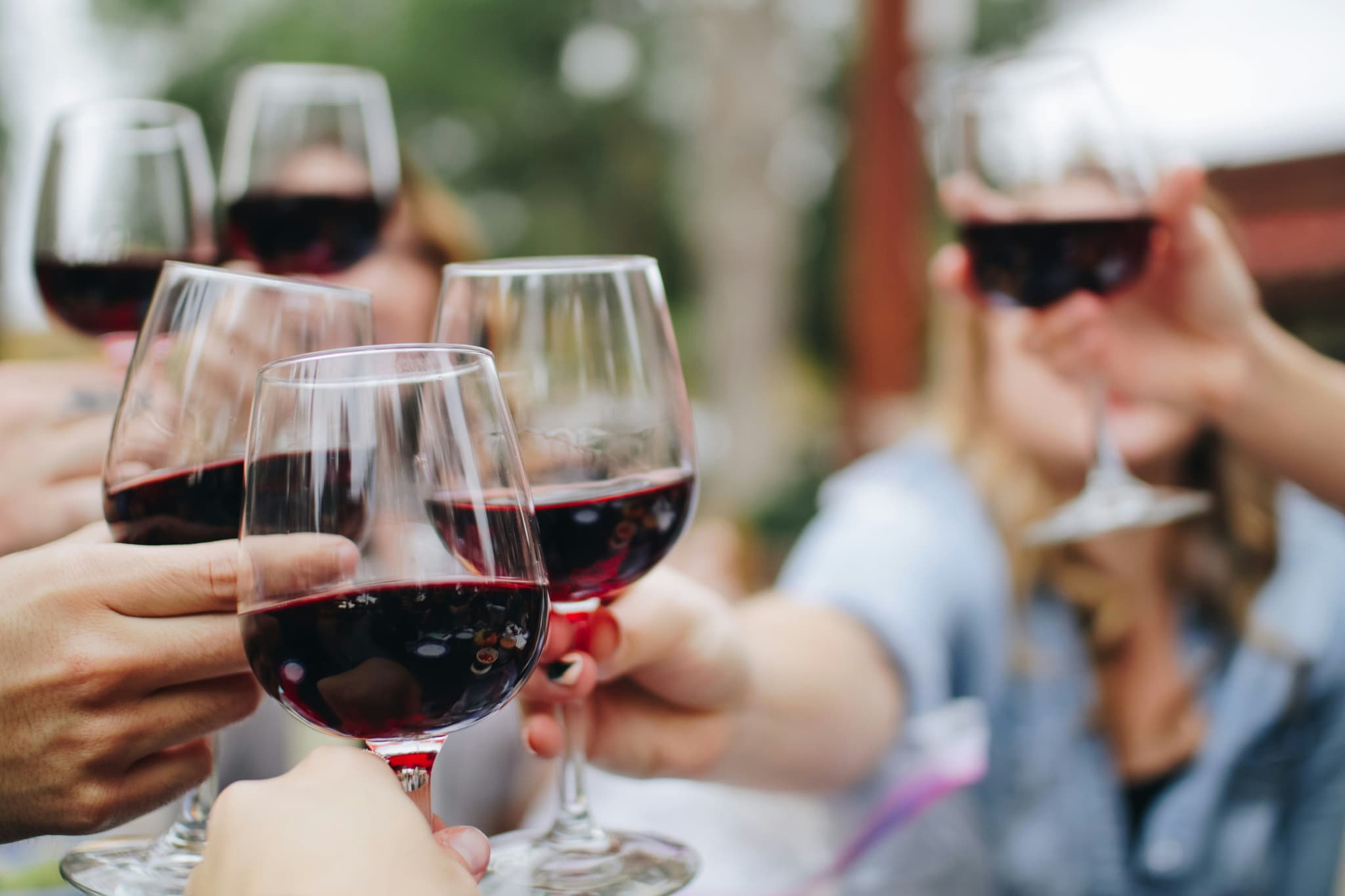 Glasses of red wine held by a group of arms