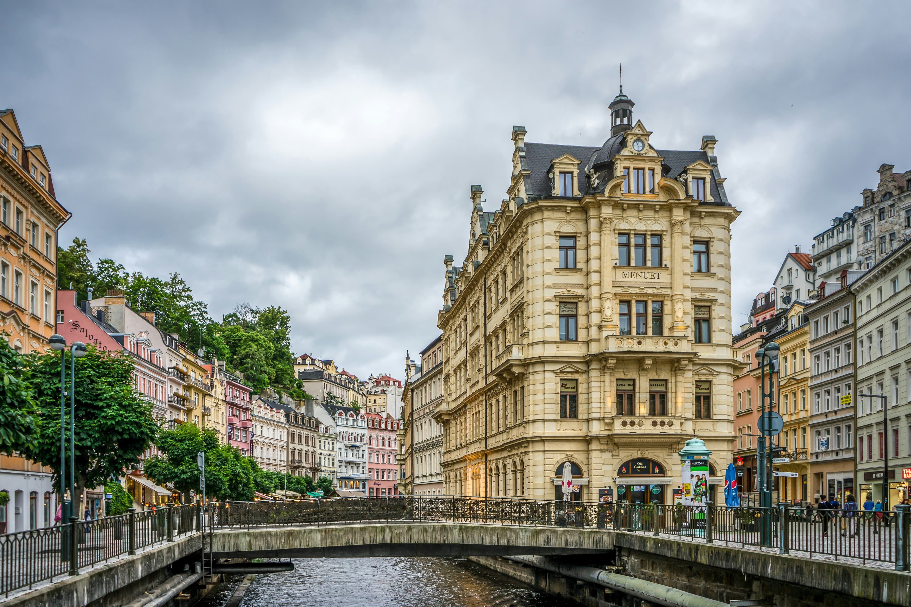 The city of Karlovy Vary, a picture of a river with a small bridge with buildings on both sides of the river.