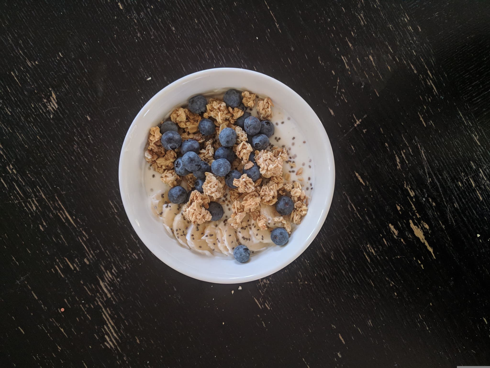 skyr yogurt in a bowl with blueberries and granola on a dark table