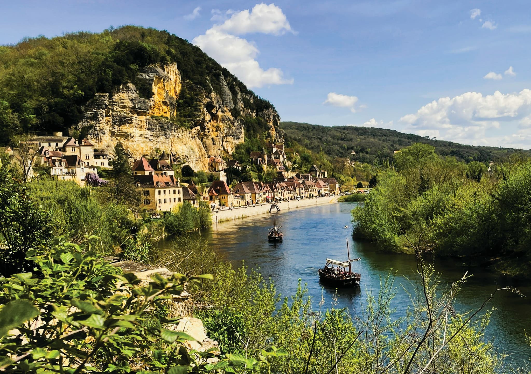 Village of La Roque-Gageac on a cliff above the Dordogne river with a small boat
