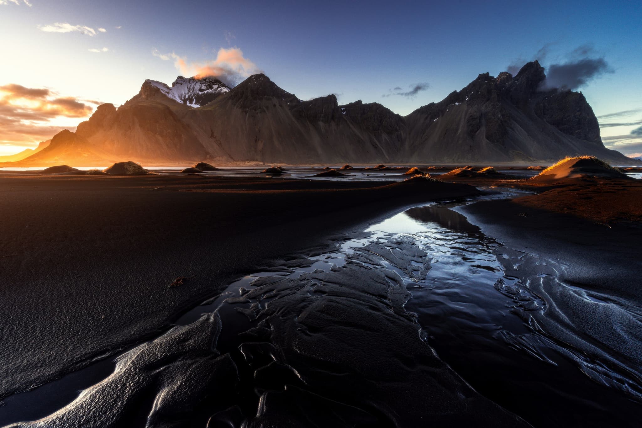 Black volcanic sand beach in Iceland with lava rock formations along the shoreline