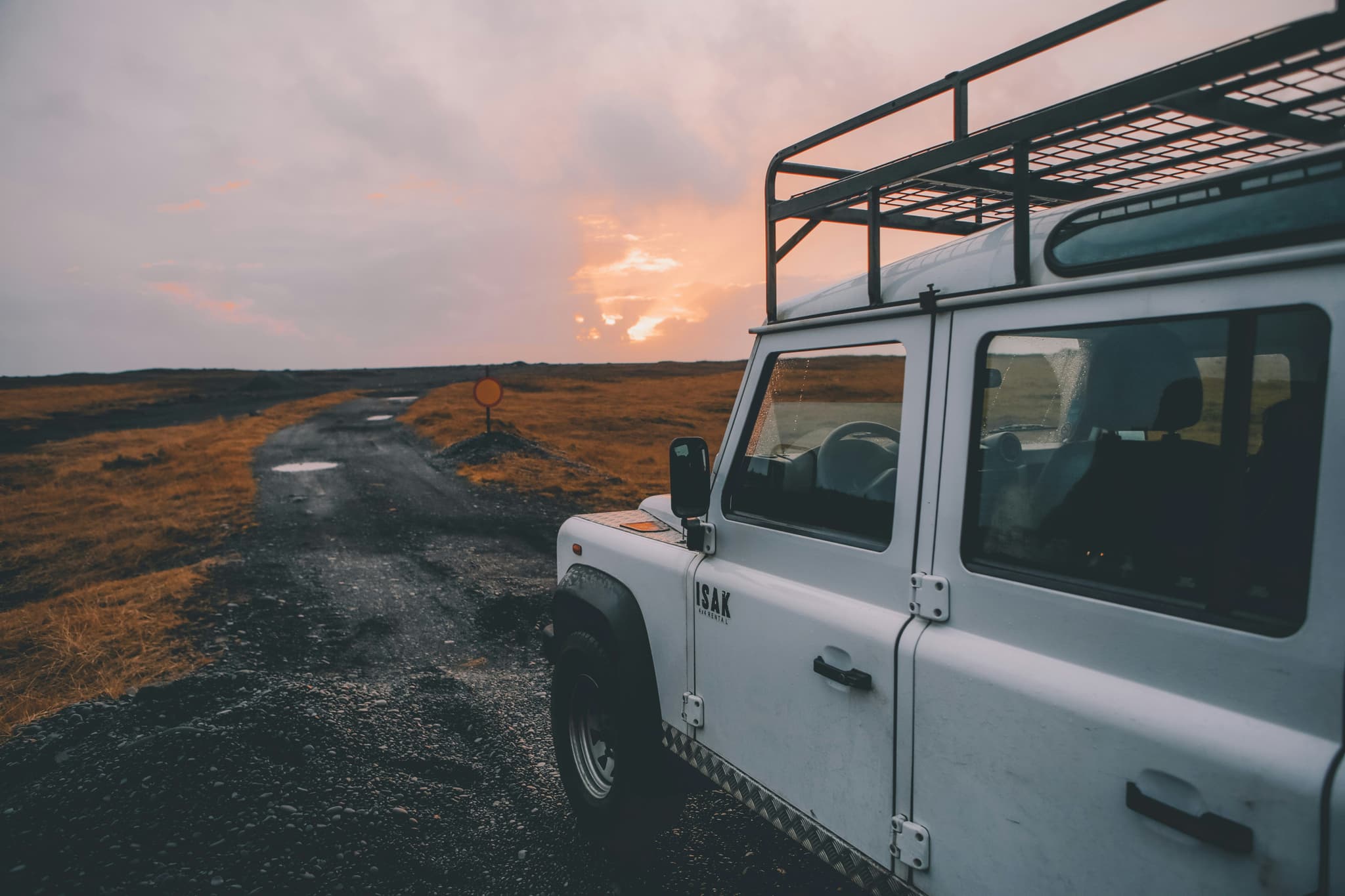 A white car driving on a rocky road in iceland during sunset