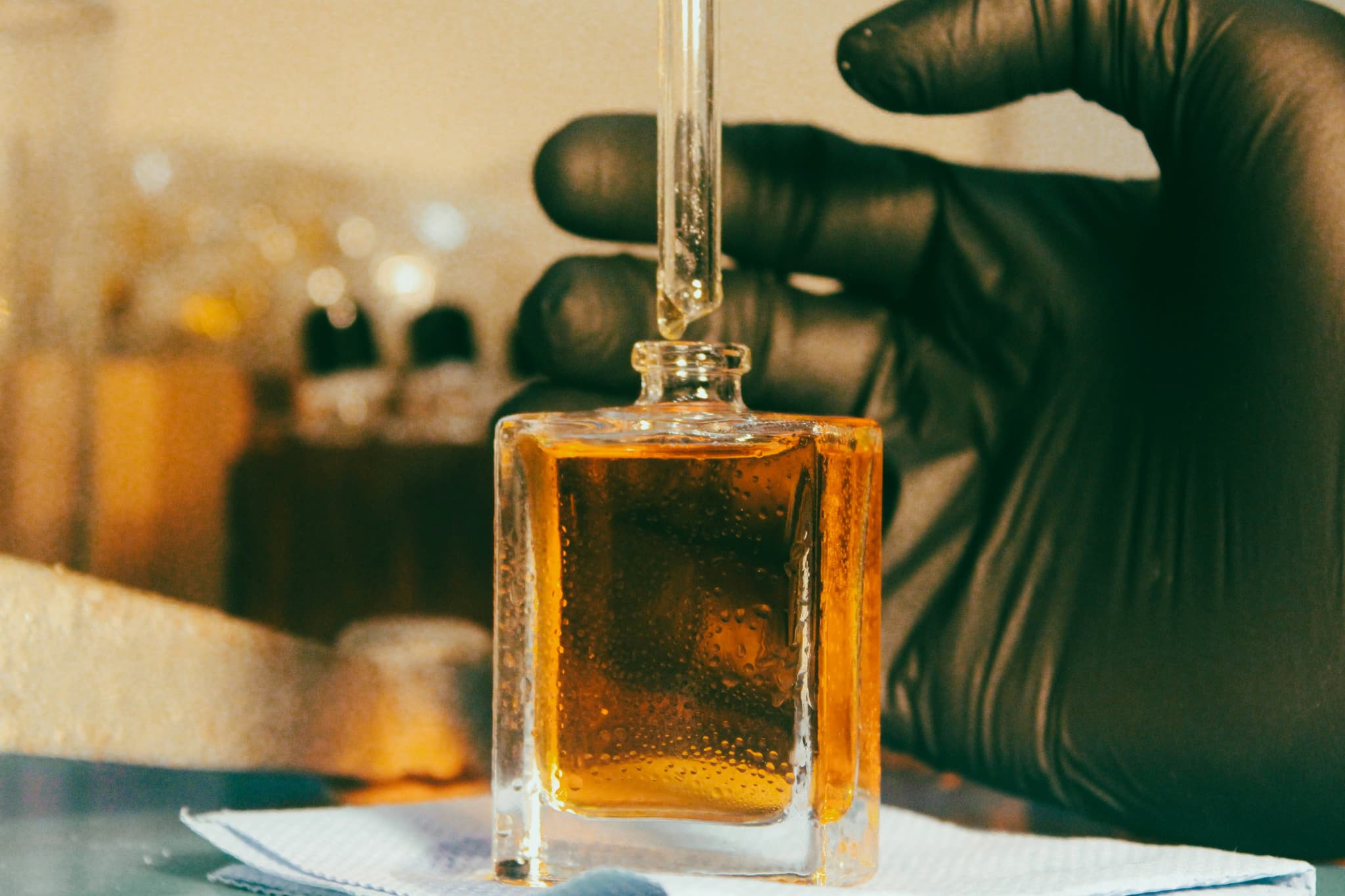 Hand with black glove filling a perfume bottle during a workshop