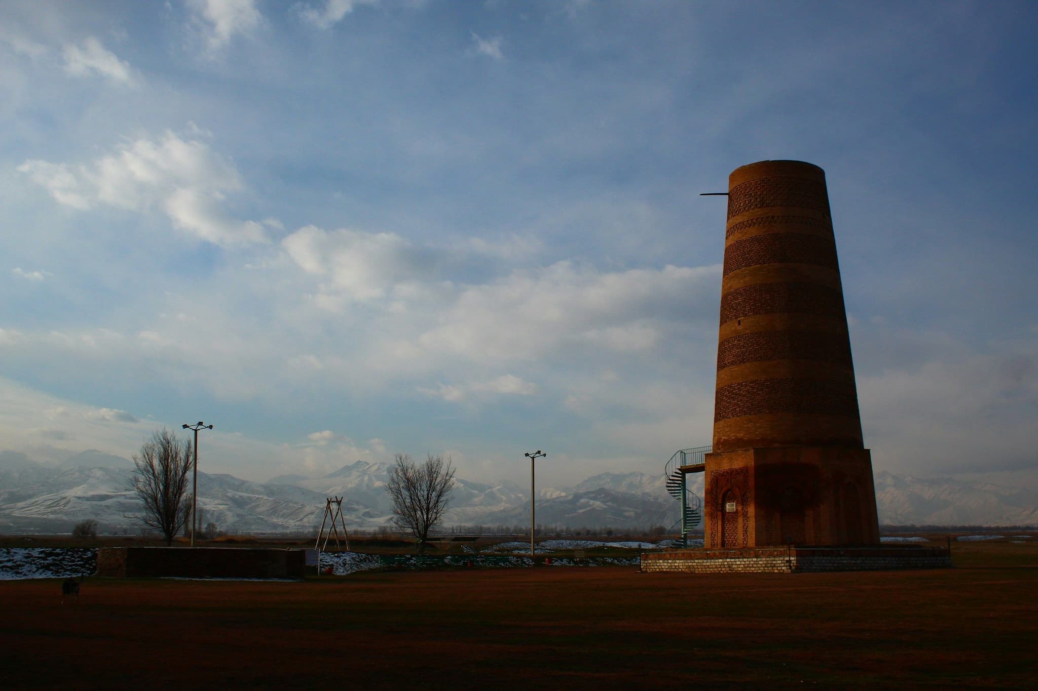 Burana Tower in a field with the Tian Shan mountains behind