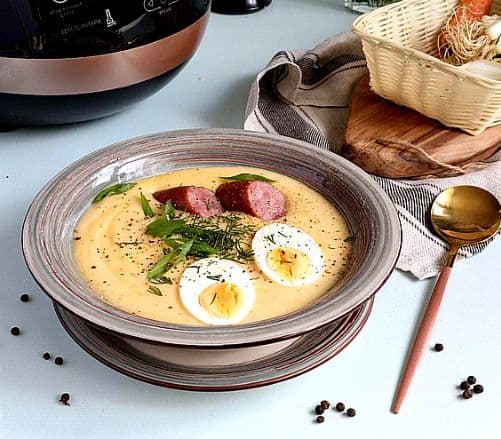 żurek soup with eggs and sausage in a bowl on a table