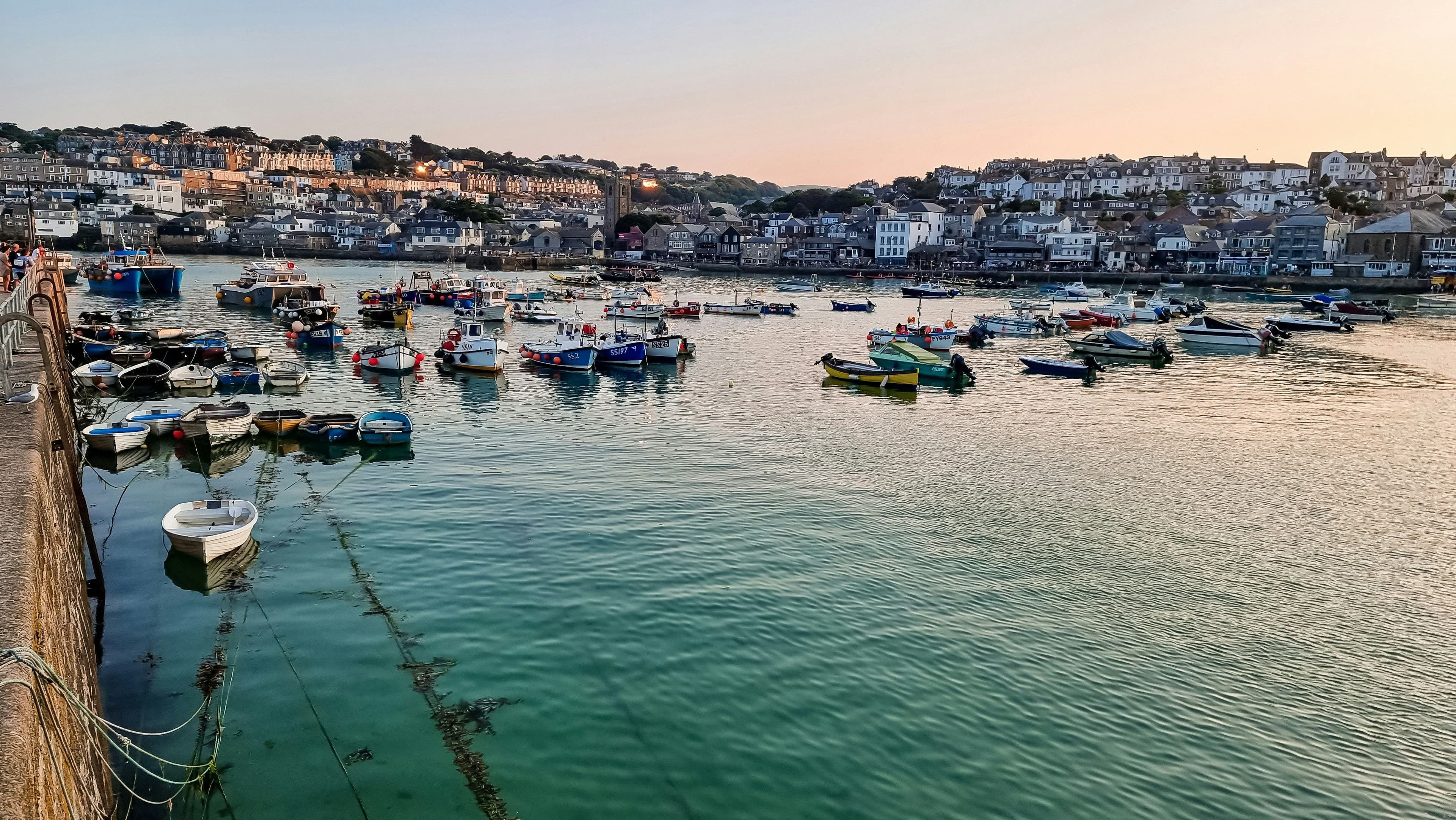 The harbour of St Ives in England with turqoise water and sail boats in the bay