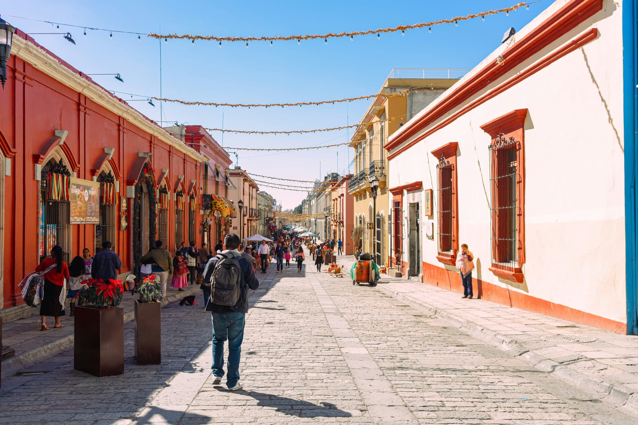 Narrow cobblestone street lined with historic stone buildings featuring tall, ornate facades; overcast sky enhances the nostalgic, quaint atmosphere.