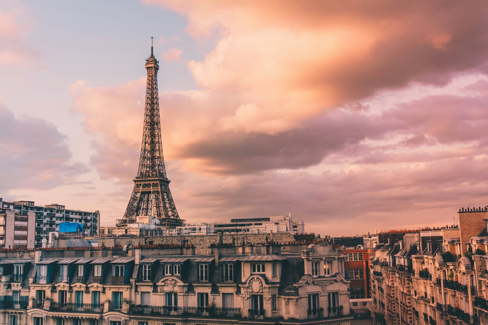 Eiffel Tower and french buildings against a pink-orange sunset sky in Paris