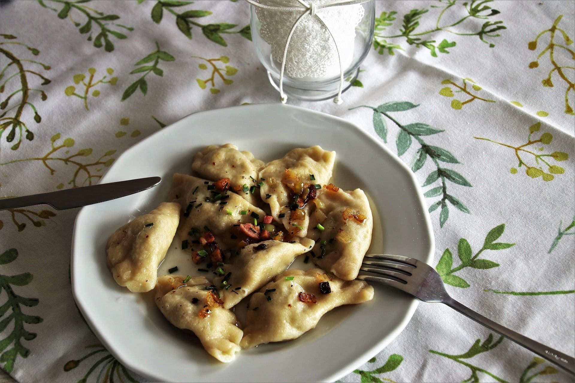 pierogi polands dish that looks like ravioli on a plate on a table with a flowery tablecloth