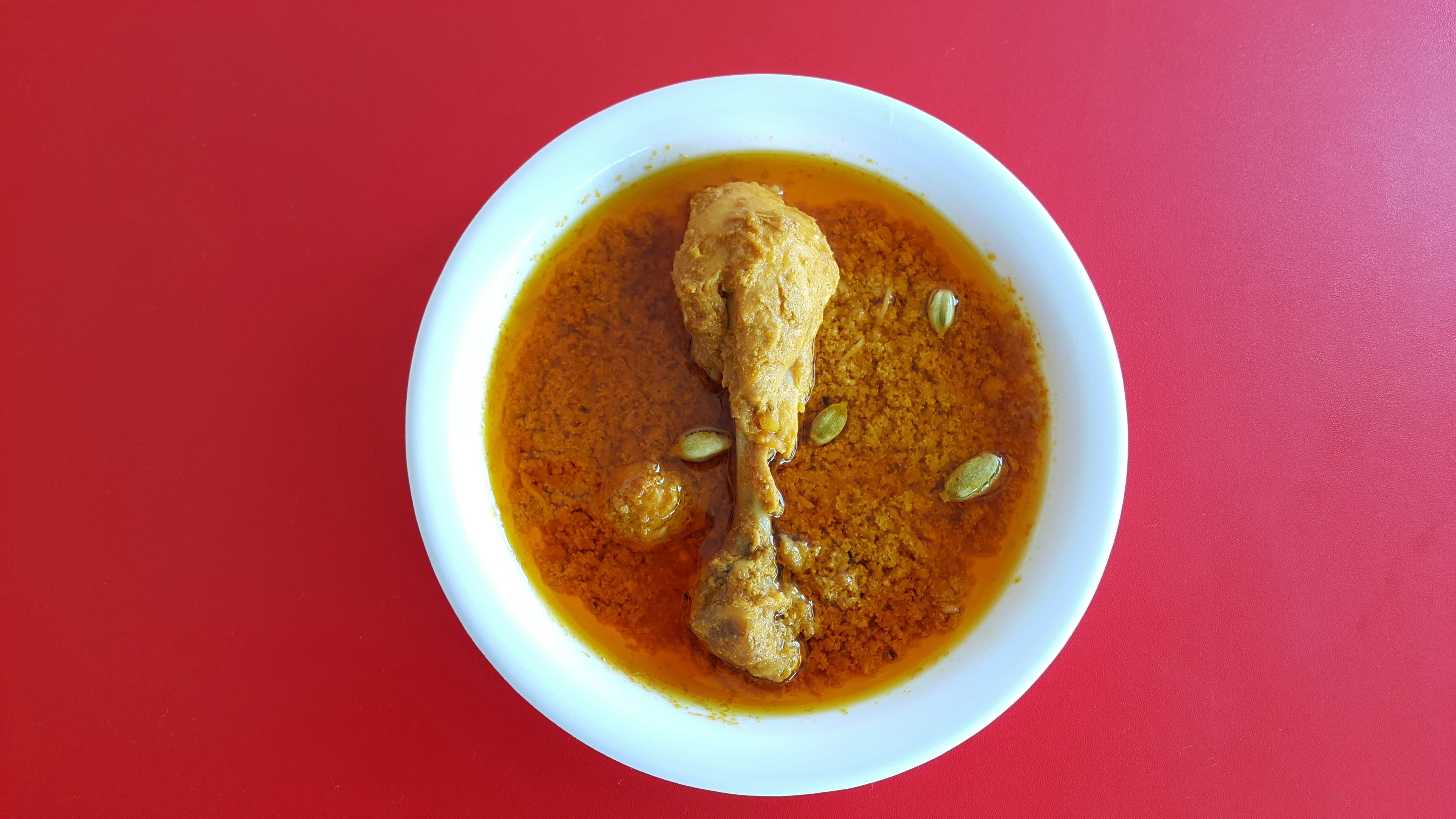 Pepián stew served in a white bowl on a red table