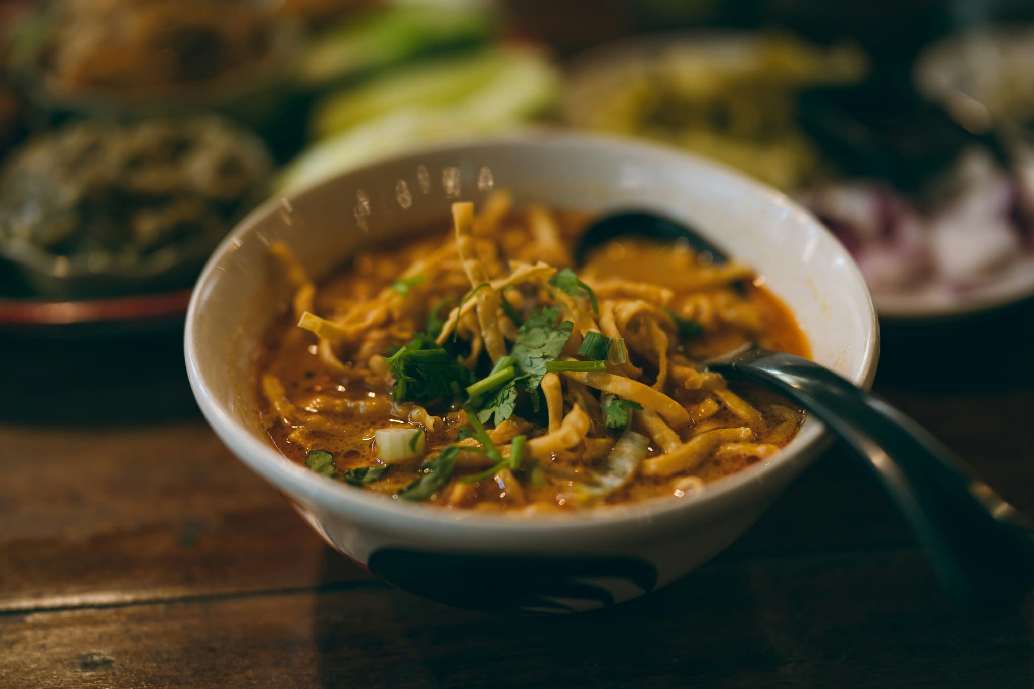khao soi in a white bowl in a dark setting