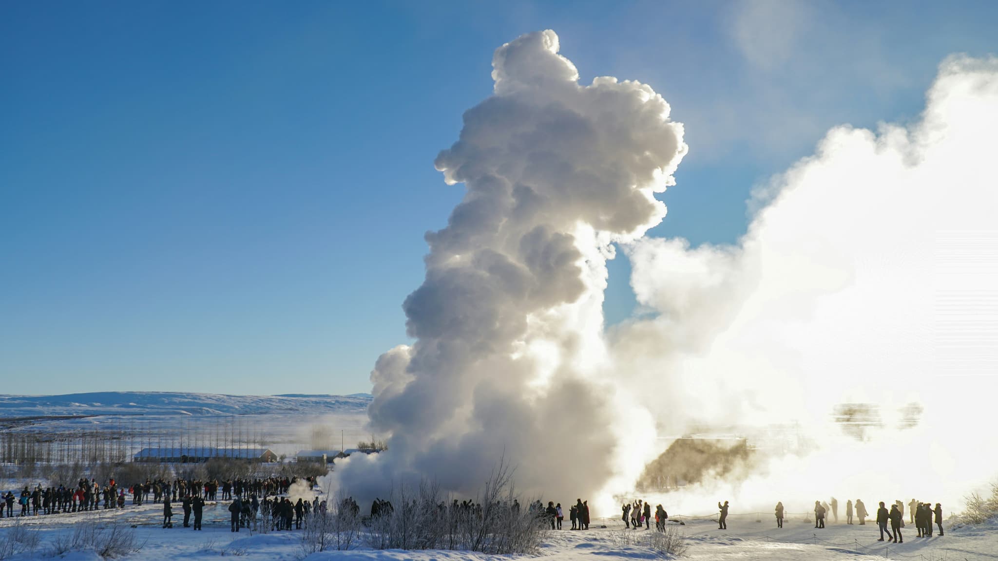Hot spring geyser erupting with a tall column of steam and water in Iceland