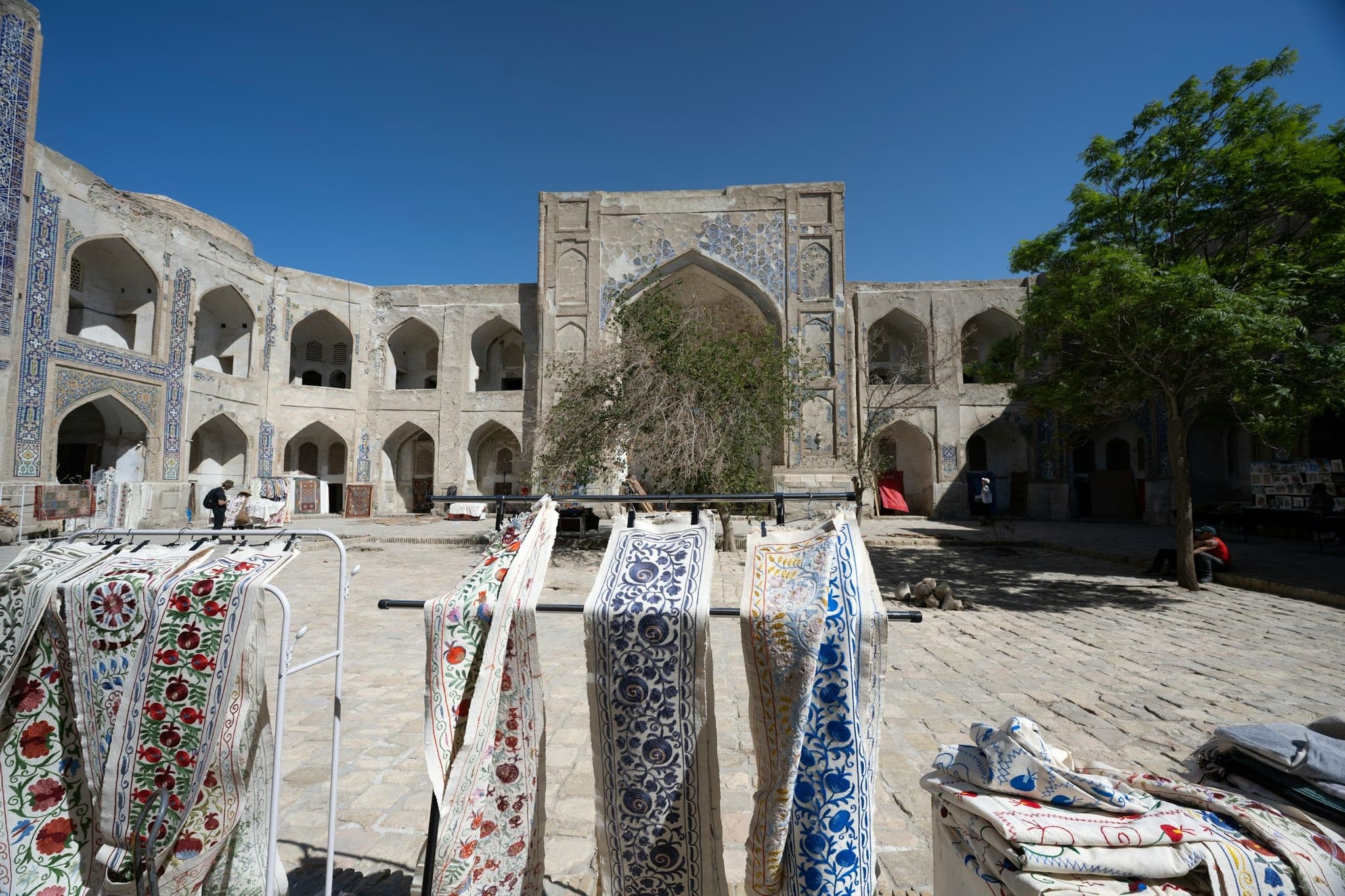 Embroidered textiles hanging in the courtyard of an old stone building