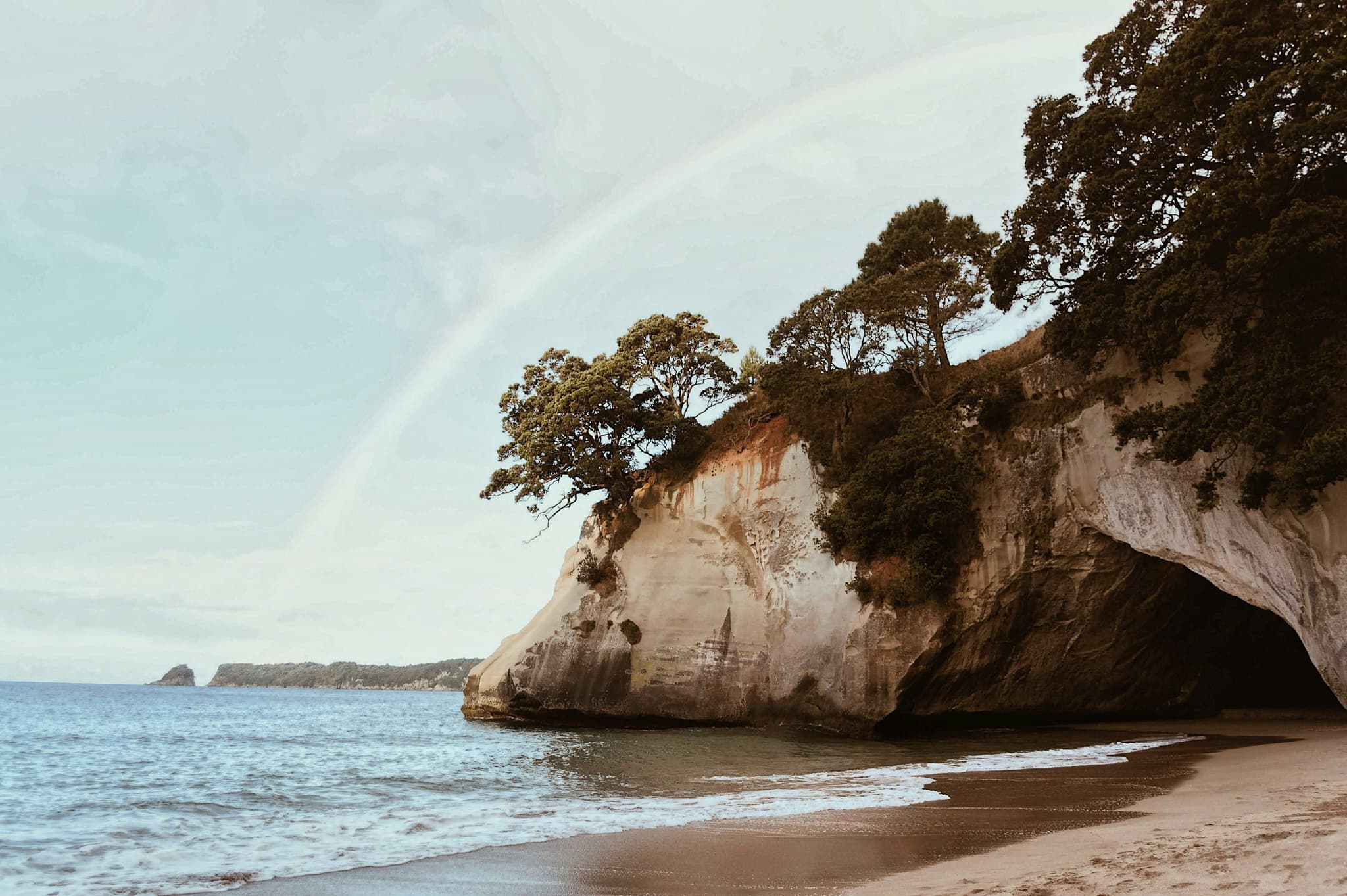 beach in new zealand Cathedral Cove, rainbow in the sky