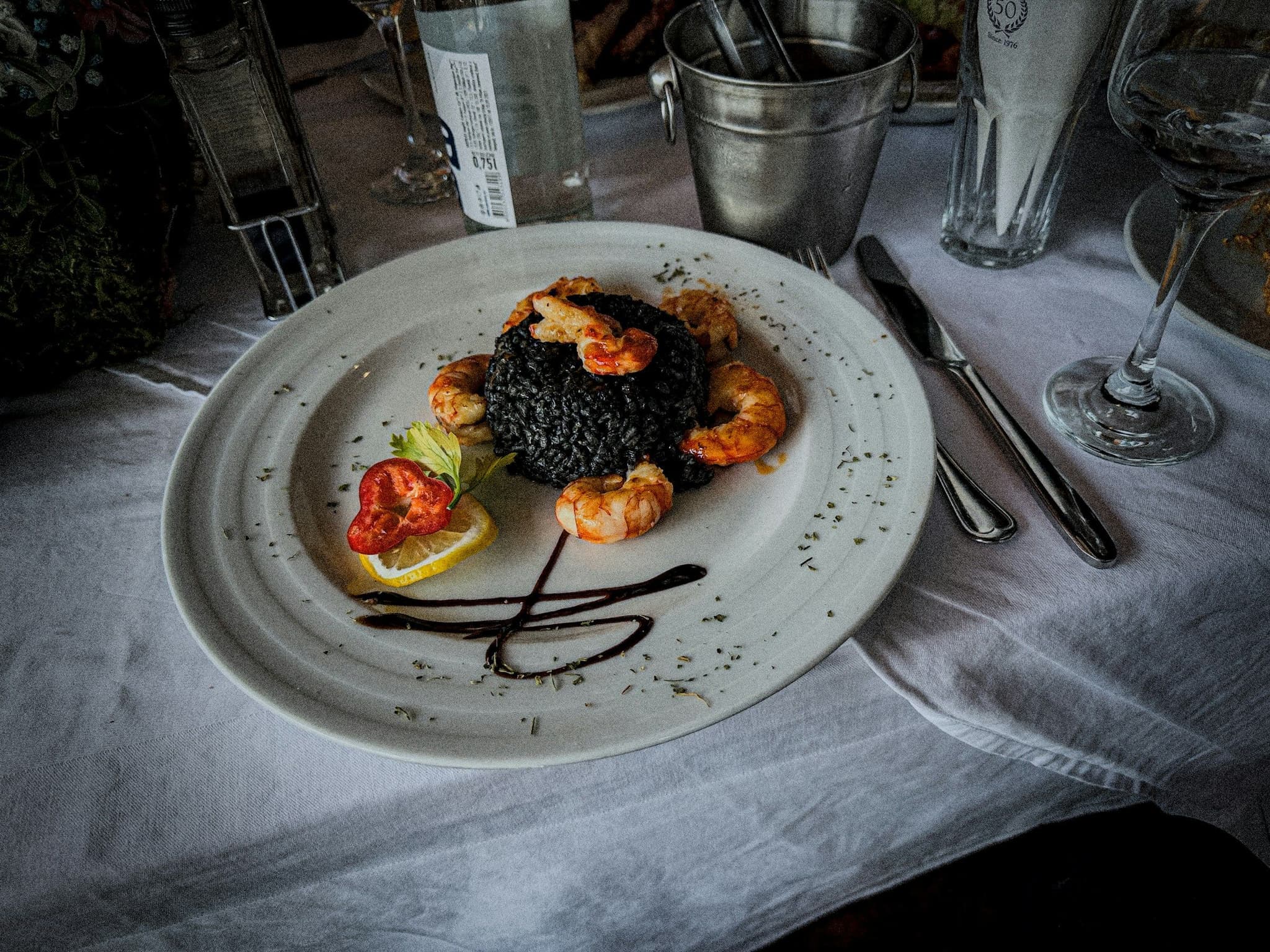 A plate of black risotto topped with shrimp