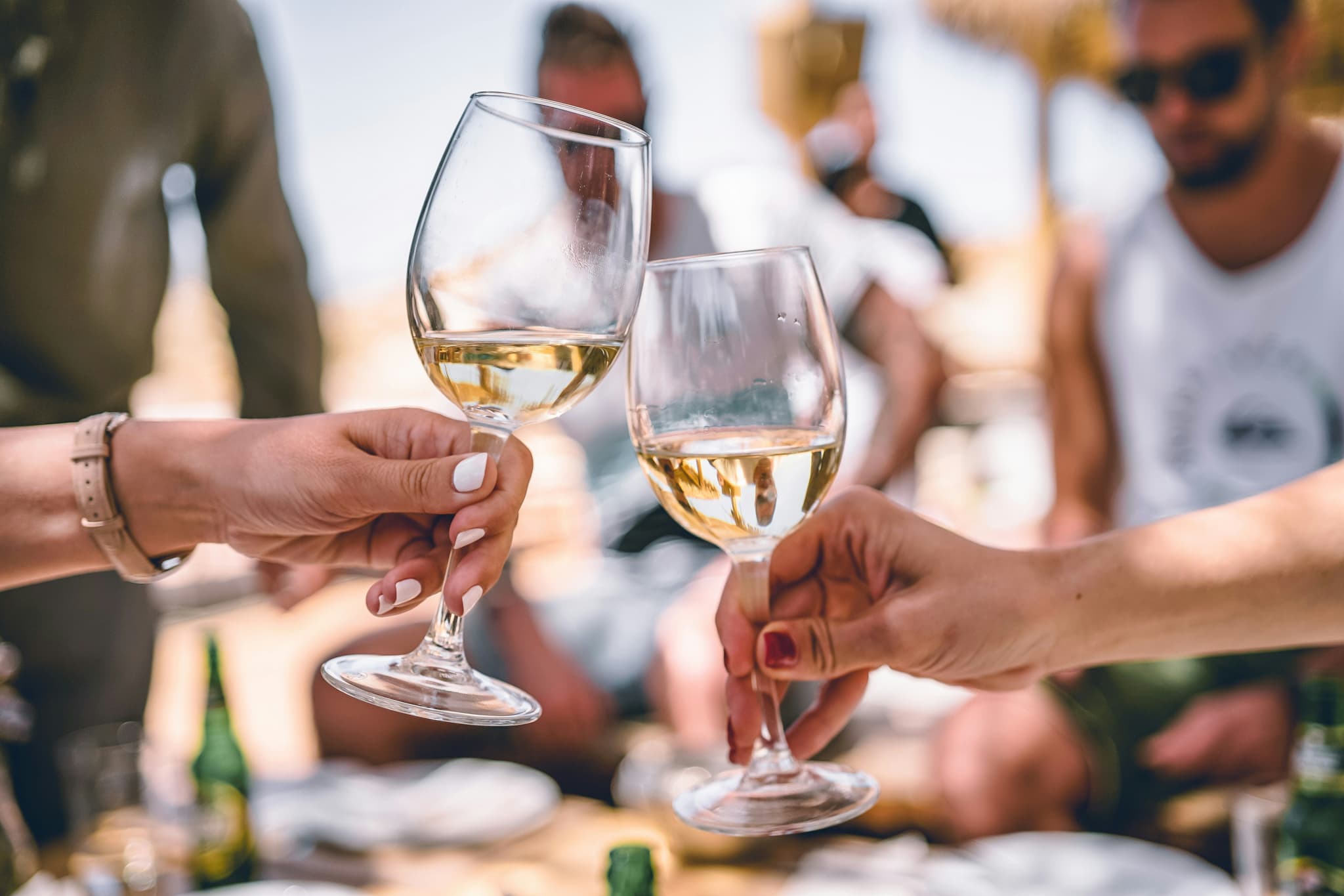 White wine and two hands with people in the background blurry