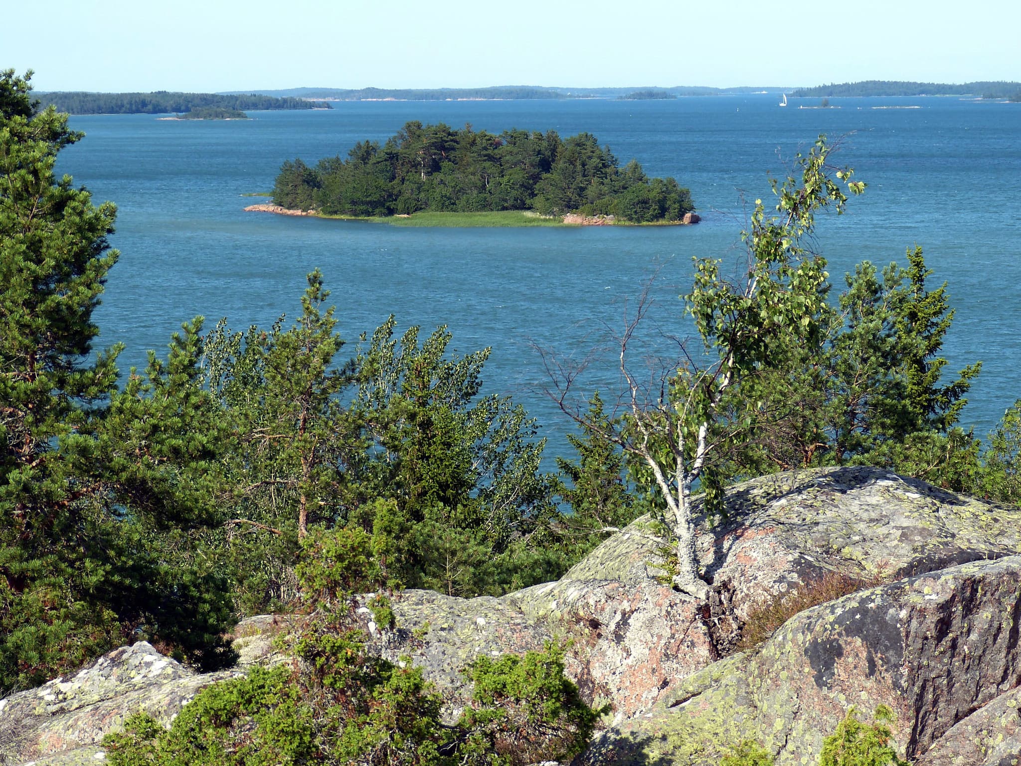 View from a rocky mountain looking over the turqoise sea with a small green island in the middle