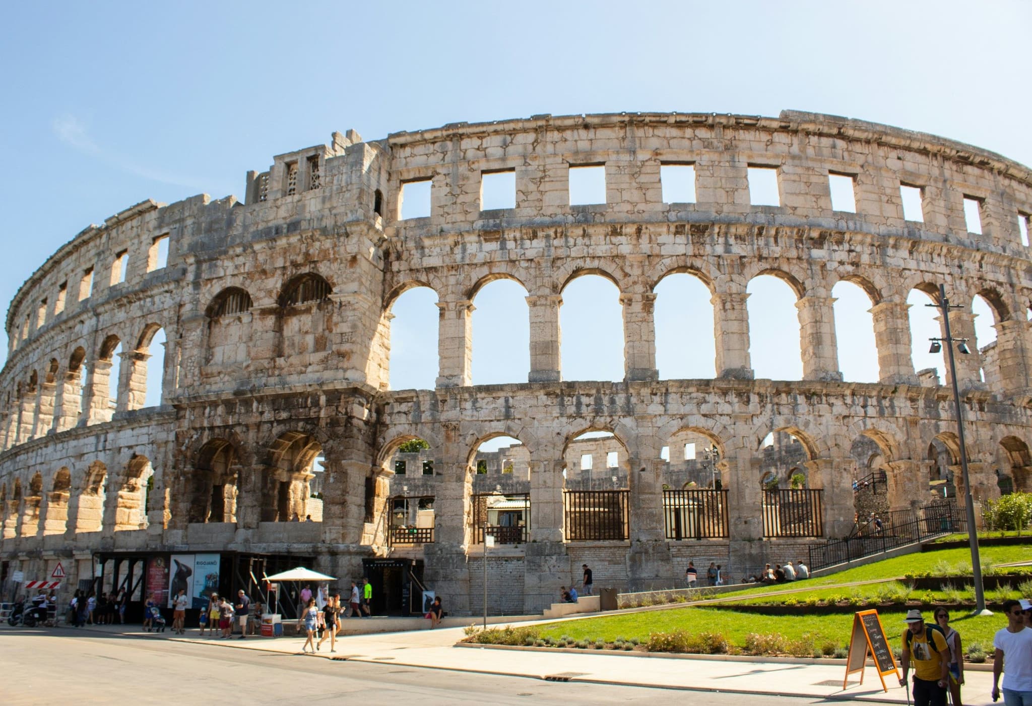 People walking past the Roman amphitheatre in Pula