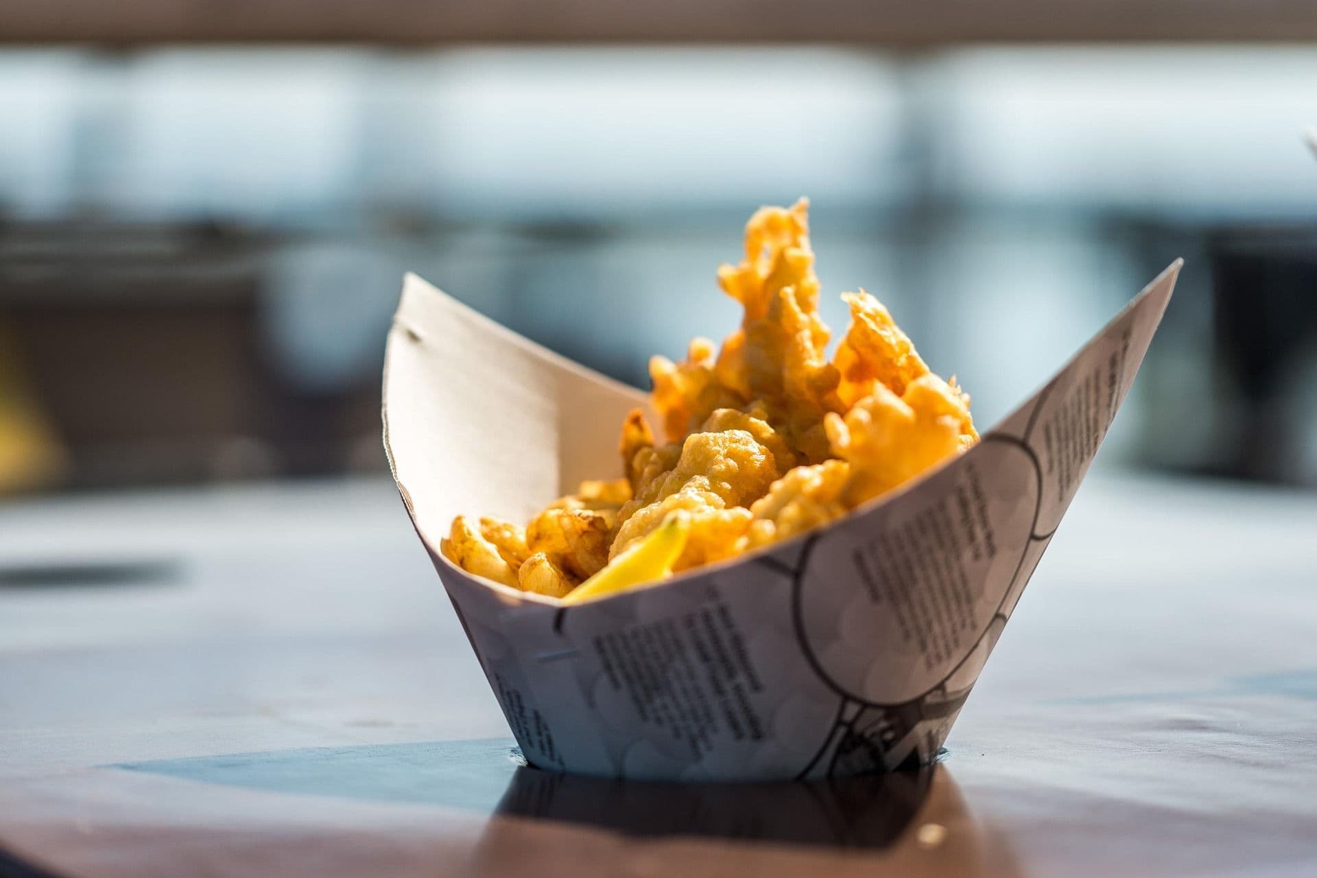 A cardboard dish with fish and chips