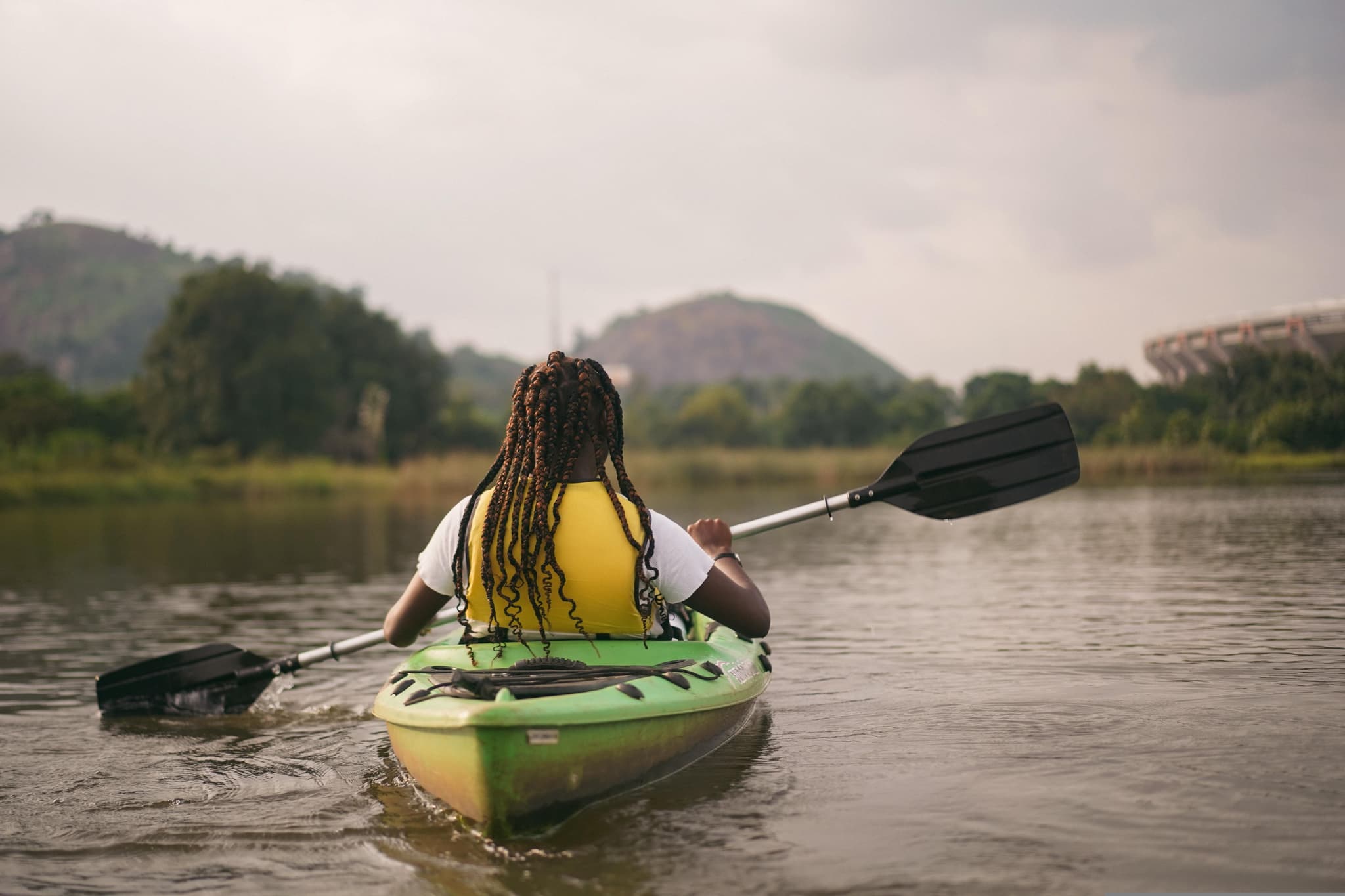 Back of a girl in a kayak on a river in Laos